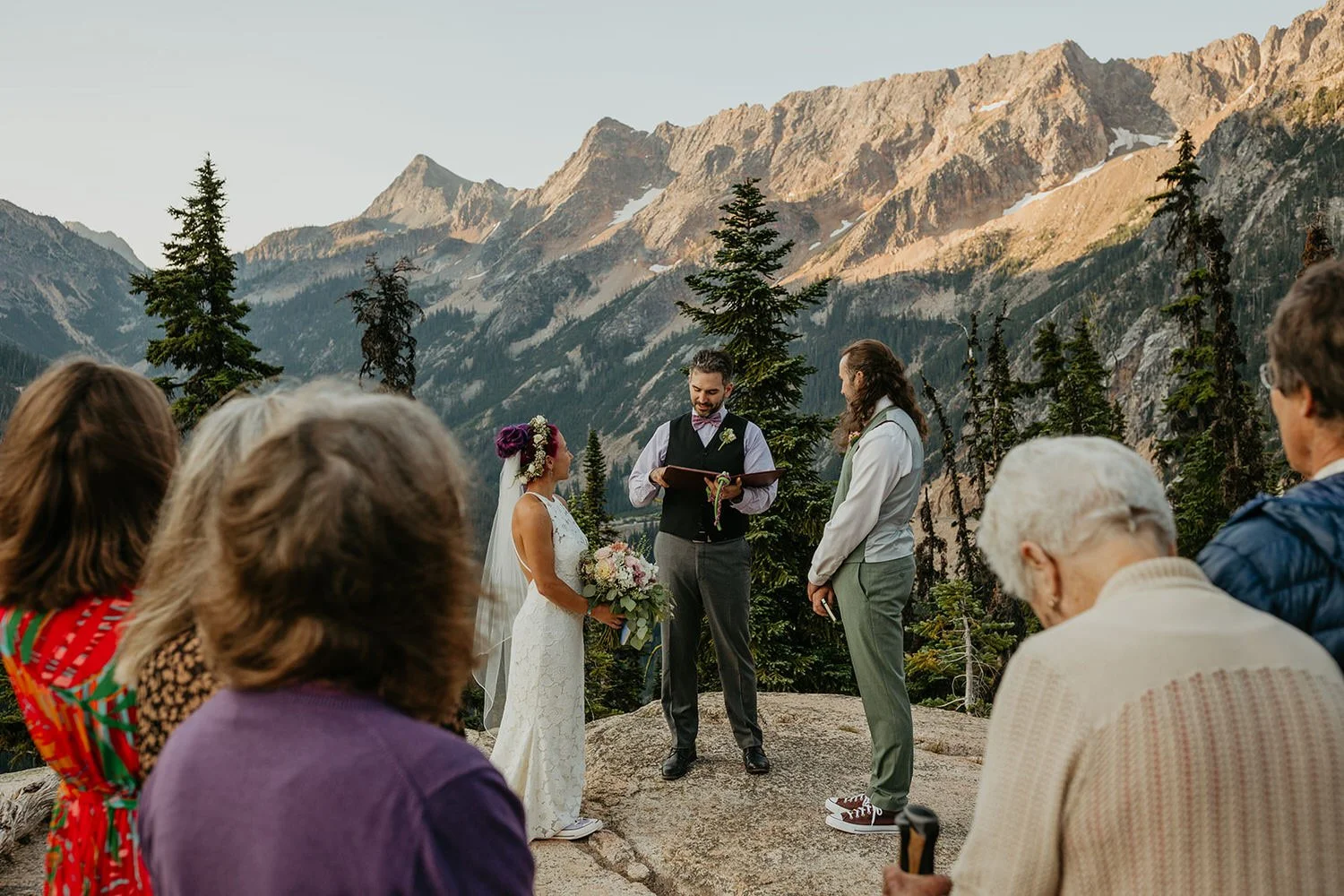 Elopement ceremony on a rocky overlook with officiant and mountain peaks in the background