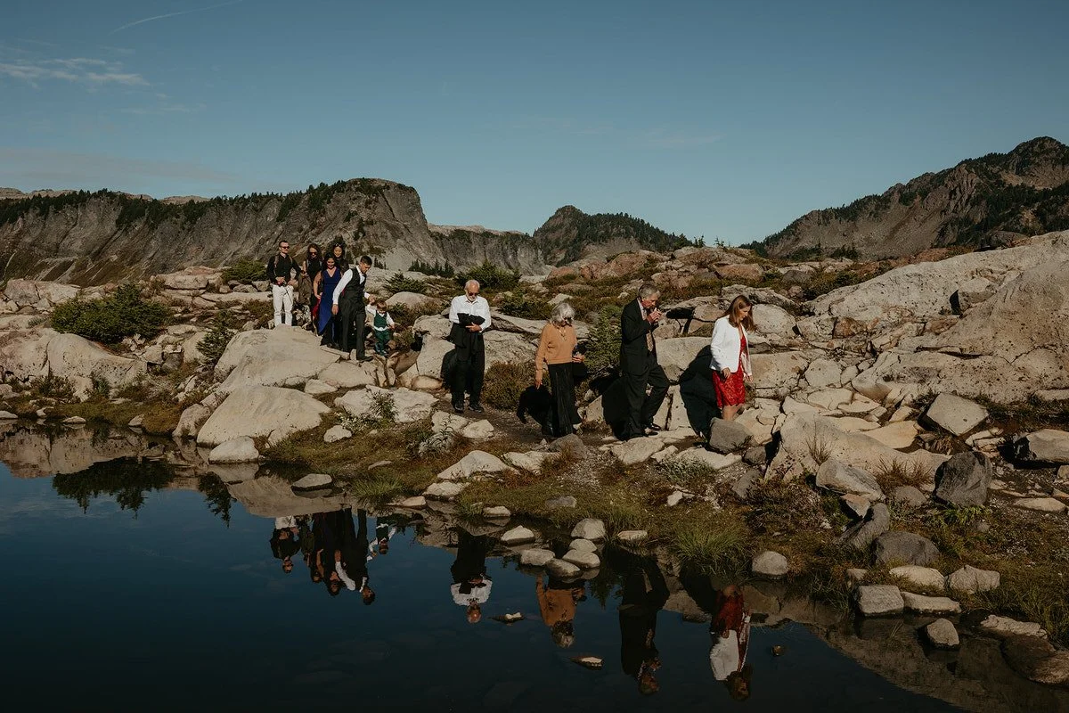 Small group of guests hiking along a rocky alpine lake during a Washington adventure elopement.