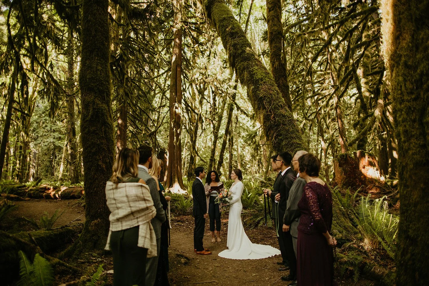 Small group gathered in a forest clearing as a couple celebrates their wedding ceremony.