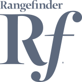 Silhouette of a person sitting and working on a laptop at a desk with a plant and a cup.