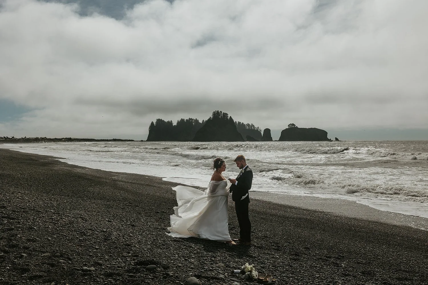 Couple standing together on a windy Washington coast beach after their elopement ceremony