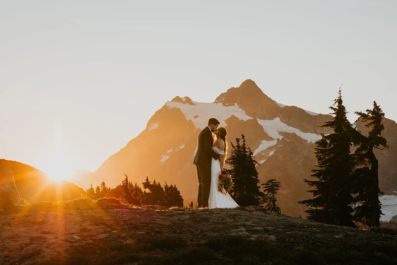 Couple standing together at sunset on a mountain ridge with Mount Shuksan in the background
