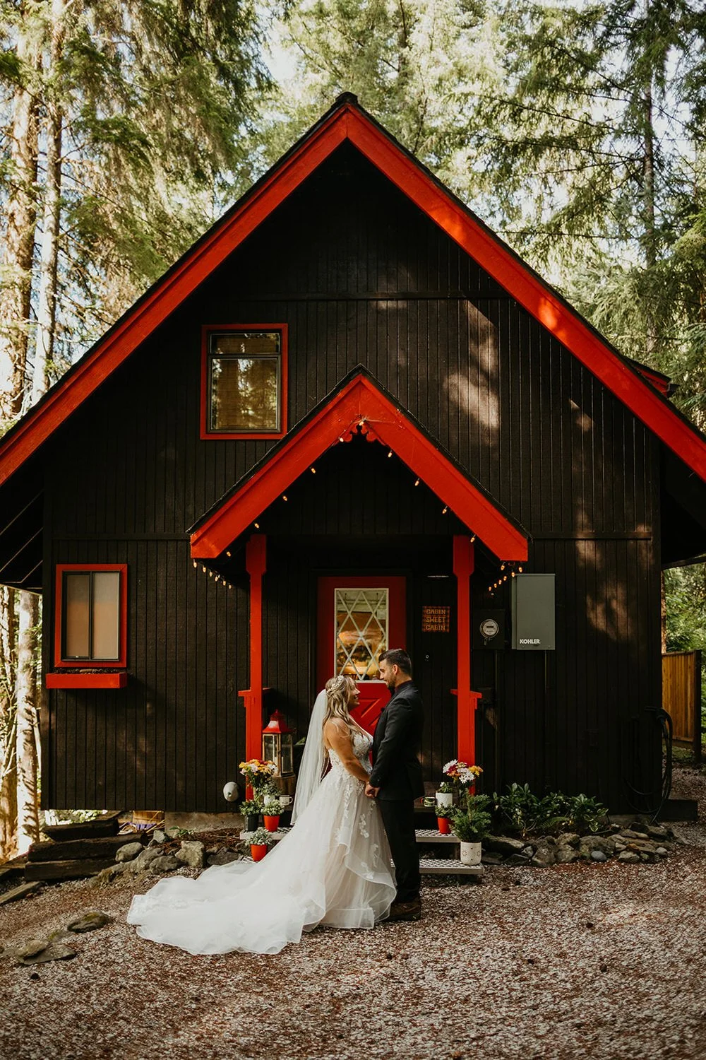 Couple holding hands outside a black A-frame cabin with red trim near Mount Baker