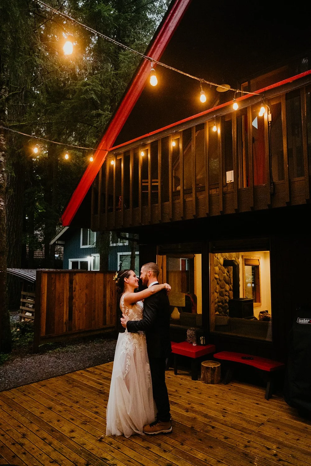 Newlyweds sharing a slow dance outside their Airbnb cabin at night, surrounded by warm string lights during their Washington elopement reception