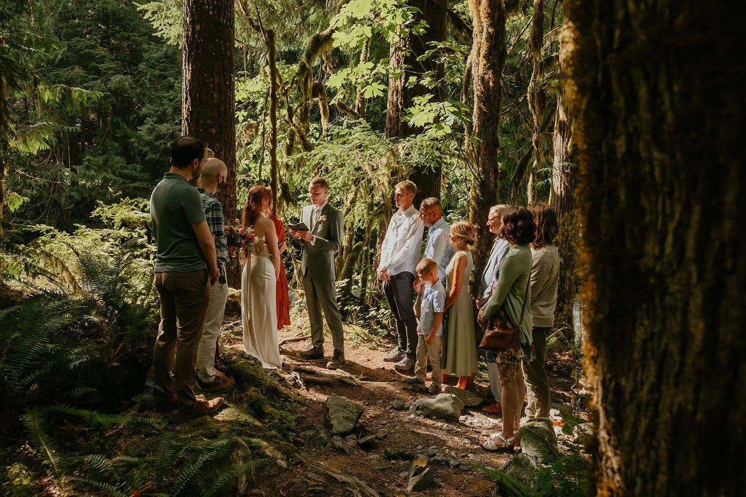 Intimate forest elopement ceremony with family gathered around the couple on a wooded trail