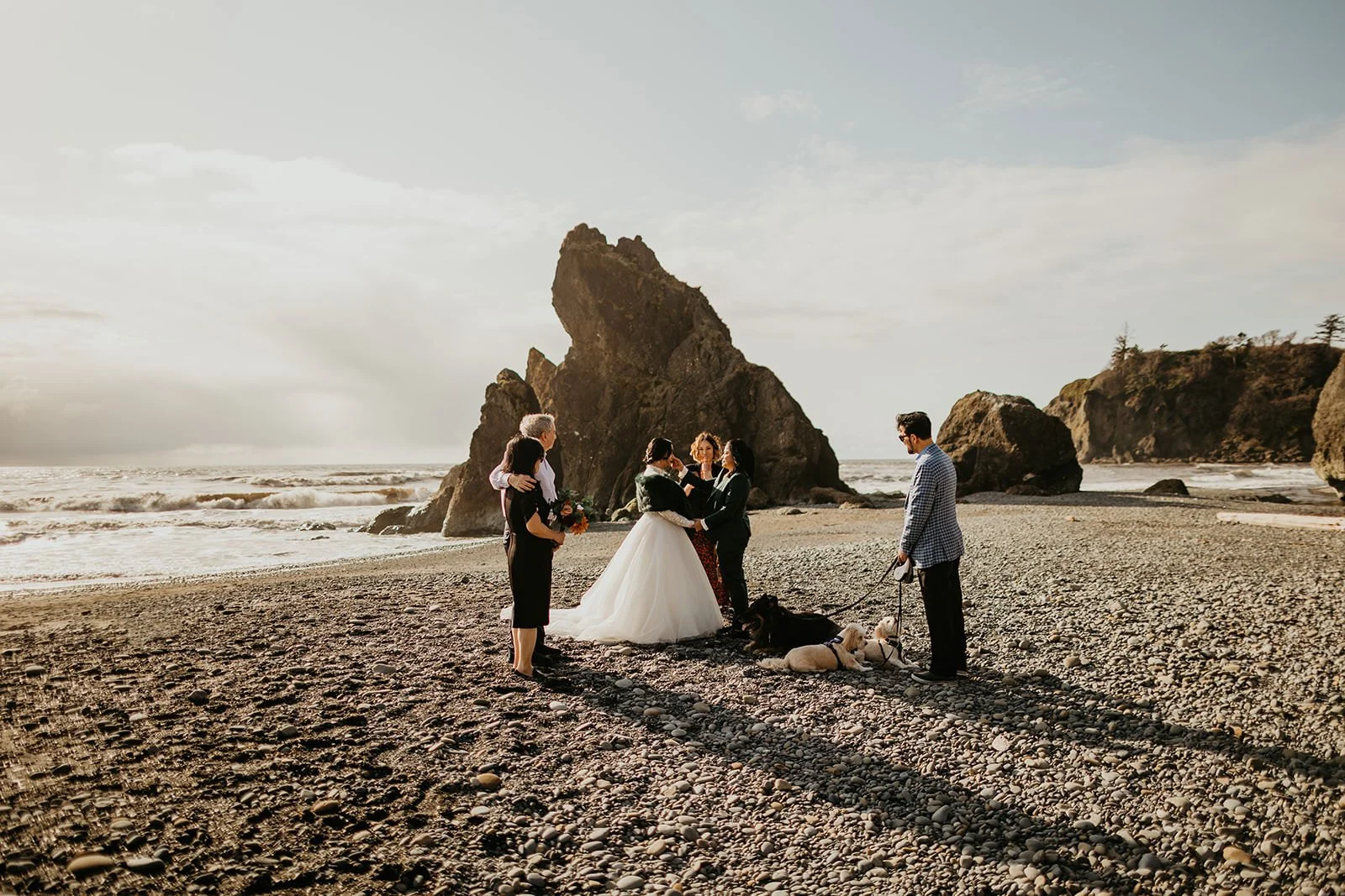 Small elopement ceremony on a Washington beach with dramatic coastal rock formations in the background.