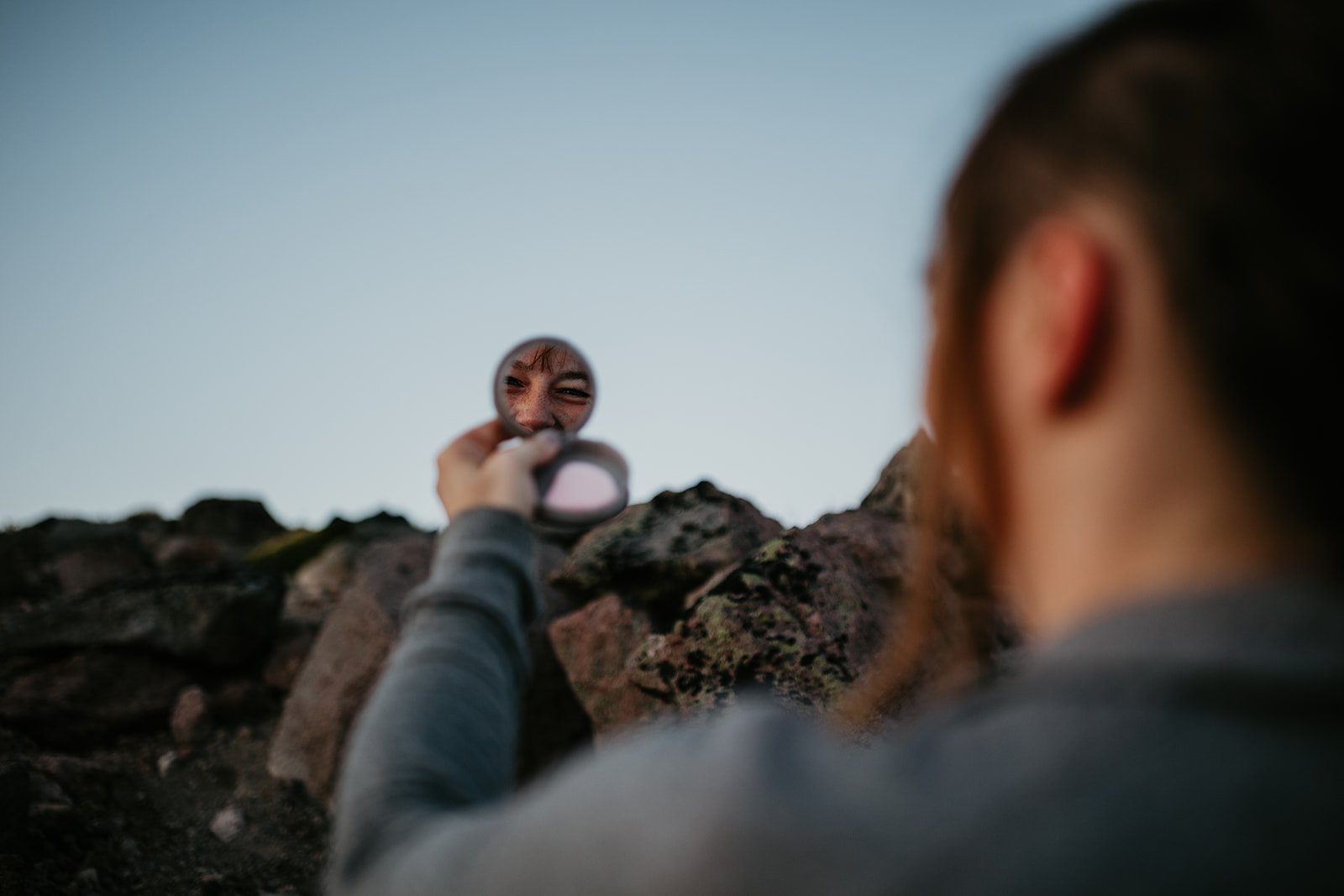 Close-up elopement portrait using a handheld mirror to capture a playful reflection in the mountains.