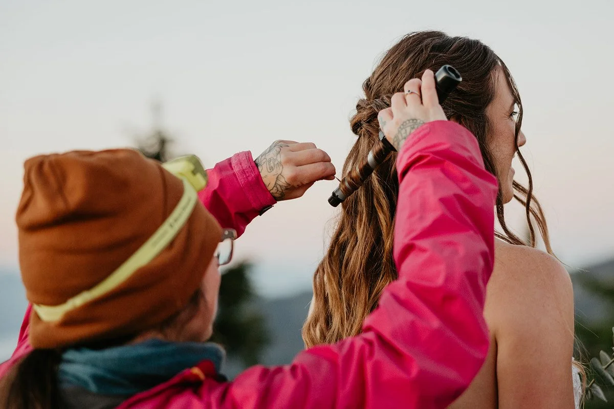 Hair and makeup artist curling bride’s hair outdoors before a Washington elopement ceremony