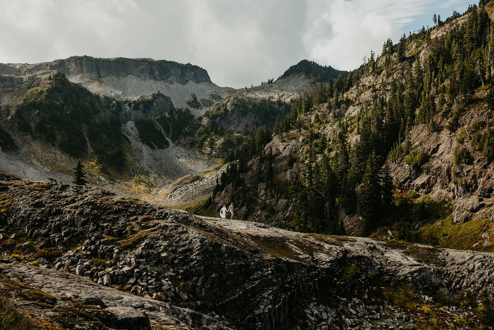 Couple eloping at Artist Point in Washington, standing on rocky alpine terrain surrounded by dramatic mountain peaks and evergreen forests.
