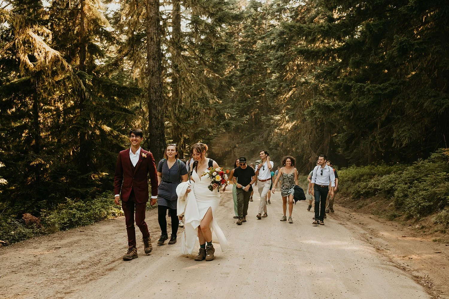 Couple and guests hiking together down a forest road during an elopement day