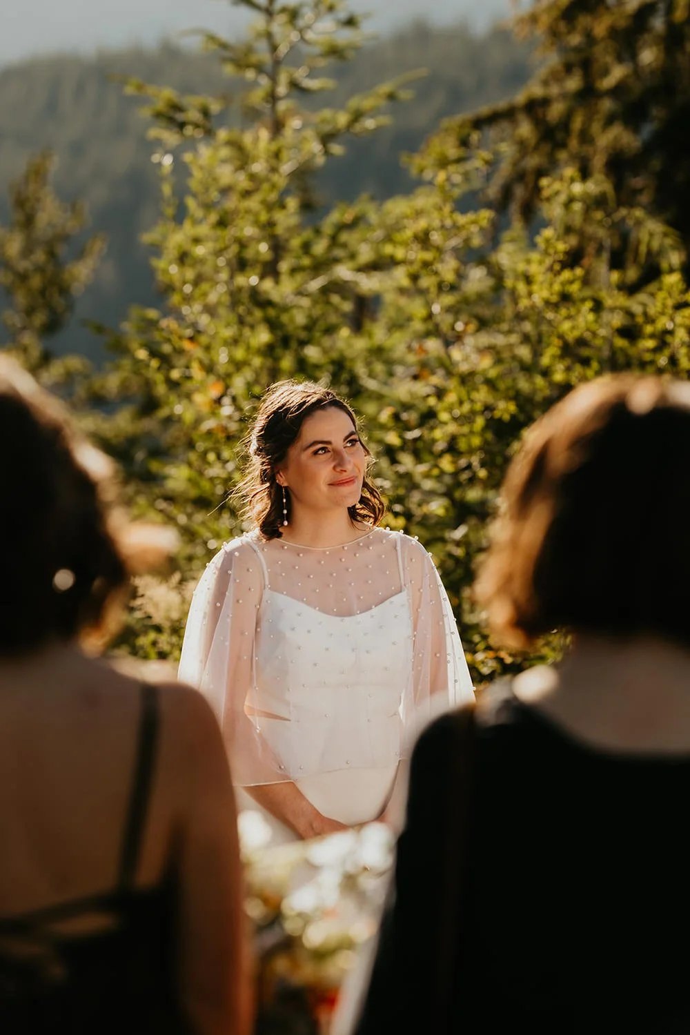 Close-up of bride smiling during an outdoor elopement ceremony surrounded by guests