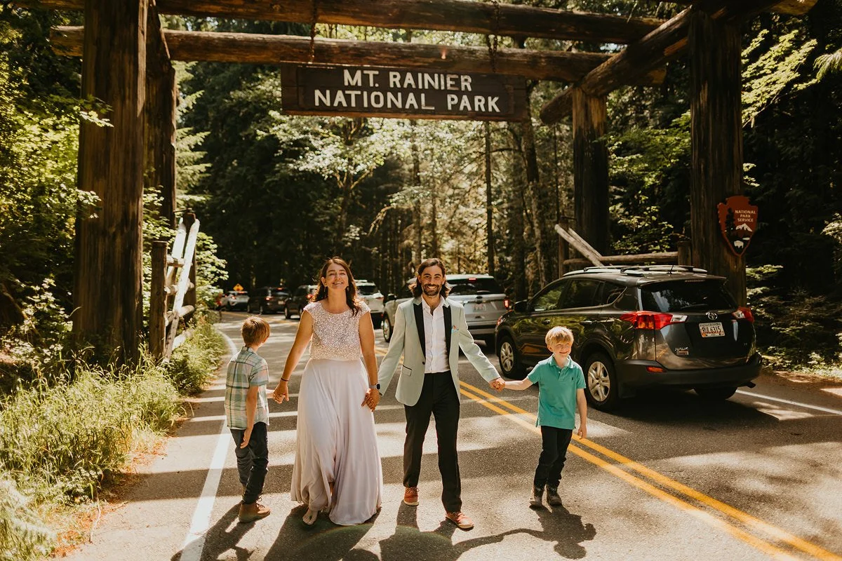 Couple and children walking under the Mount Rainier National Park entrance sign during an elopement day