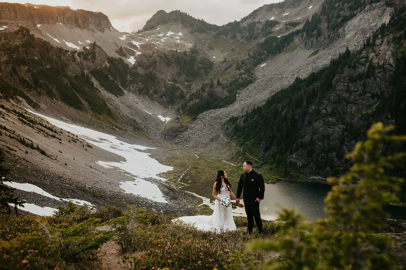 Eloping couple walking together along a mountain ridge in the North Cascades with layered peaks in the distance