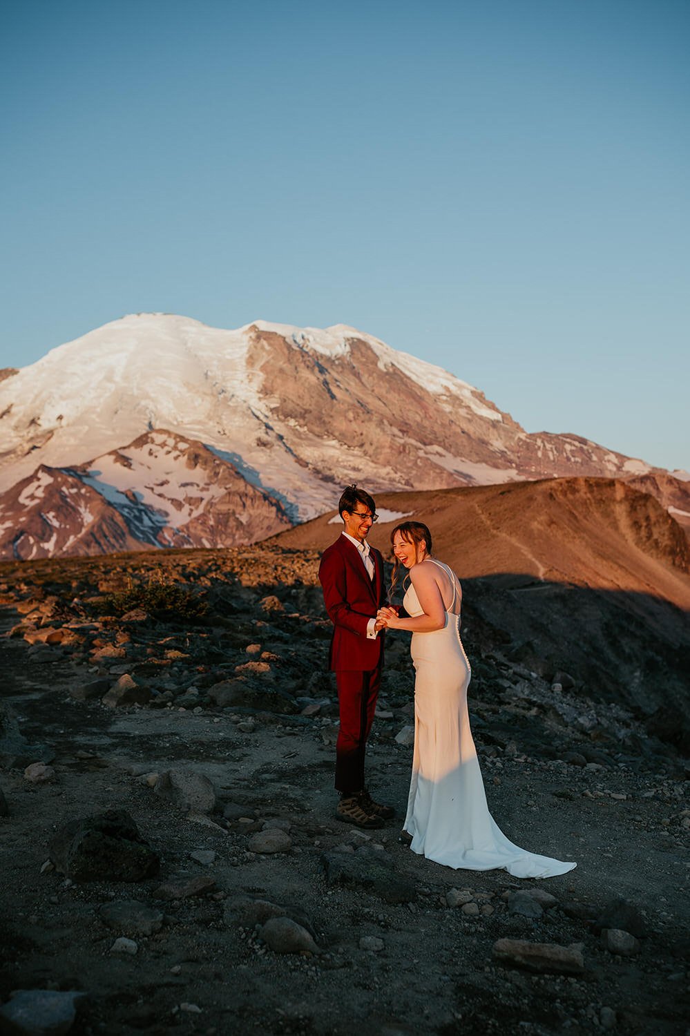 Couple holding hands and laughing at sunset with Mount Rainier towering in the background