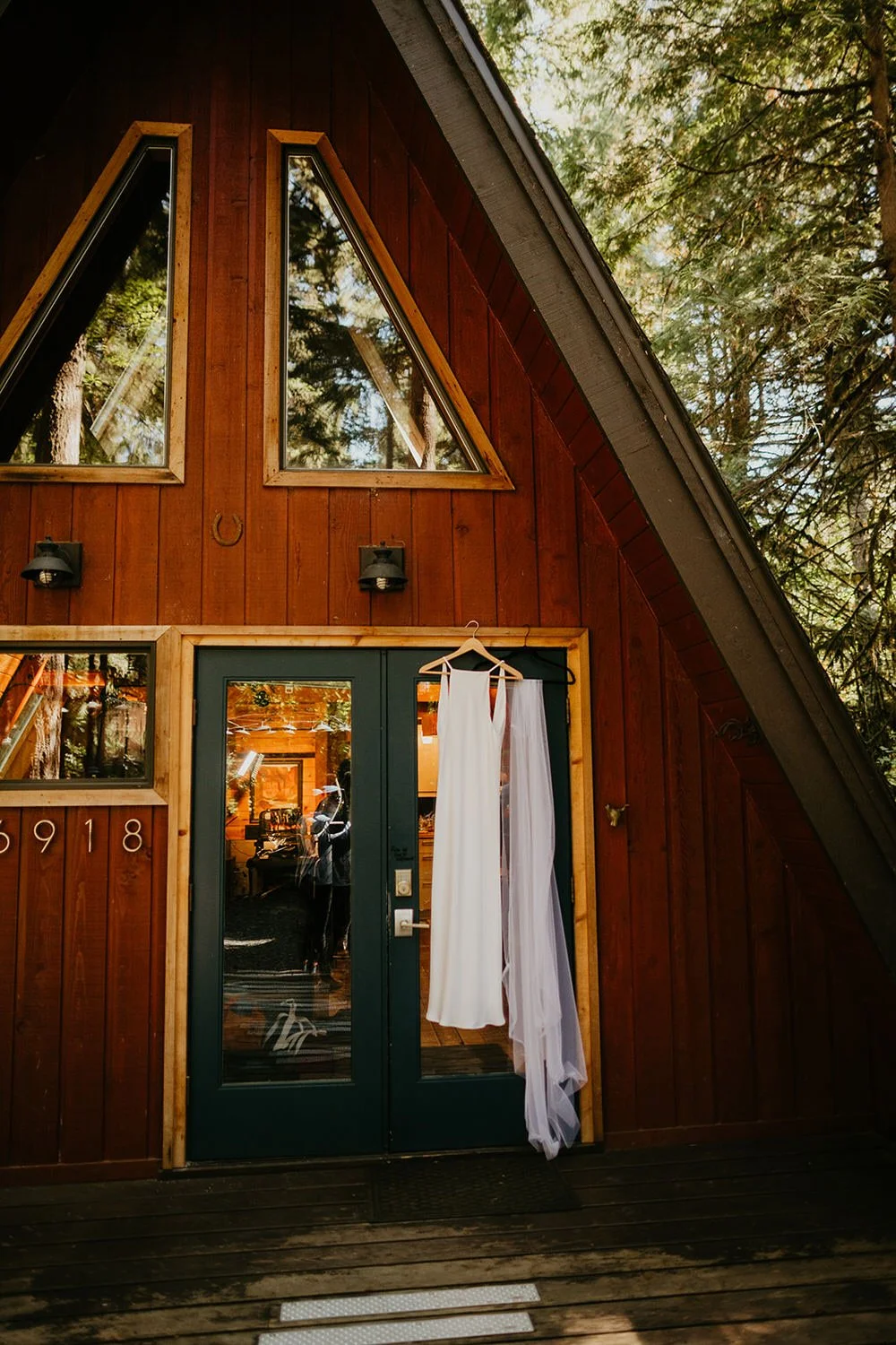 Wedding dress and veil hanging on an A-frame cabin's front door before the ceremony