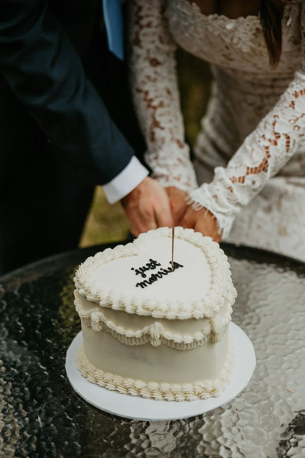 Couple cutting a heart-shaped white elopement cake decorated with the words 'just married' during their private cabin reception