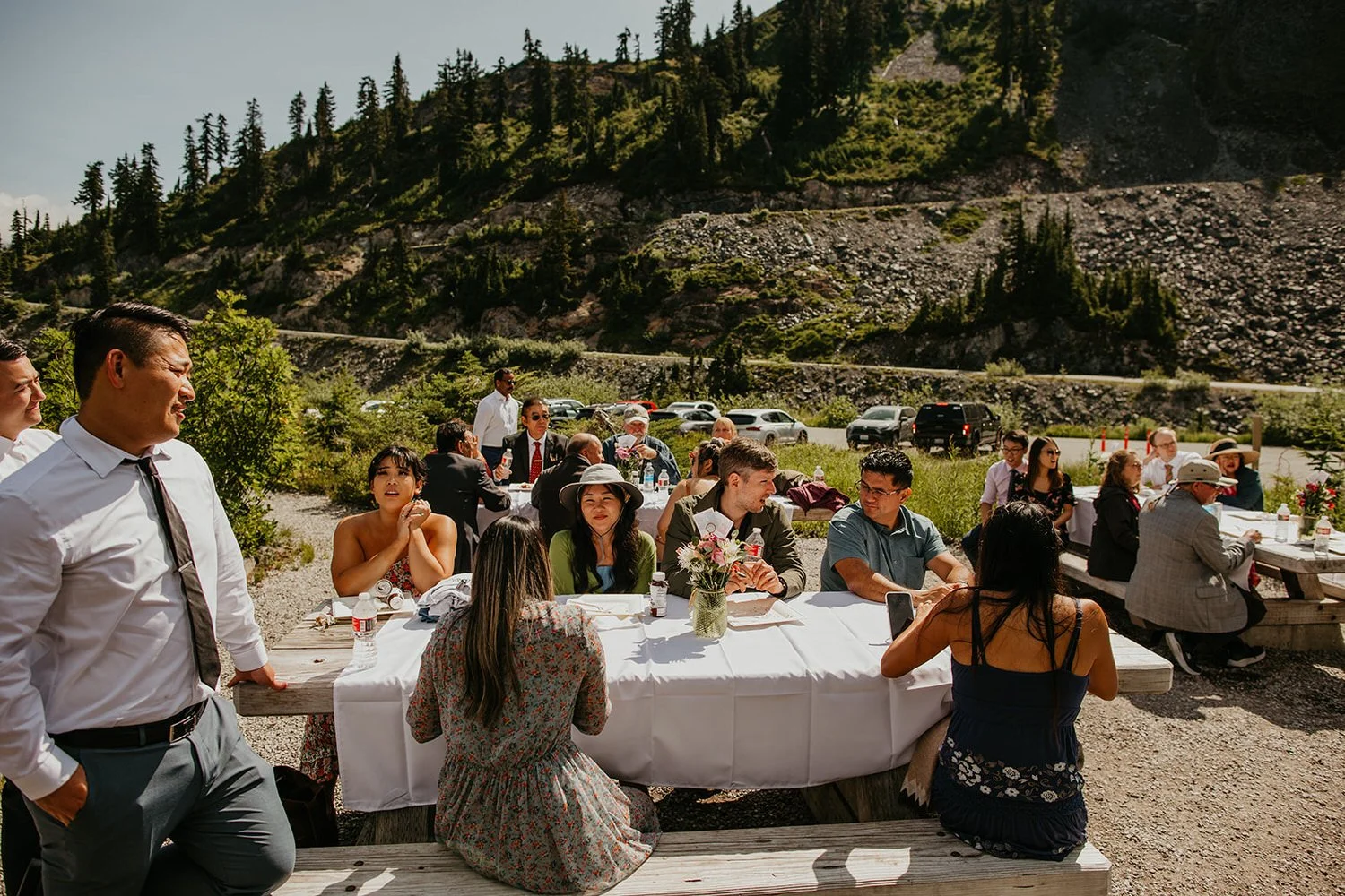 Guests seated at decorated picnic tables during an Austin Pass reception with mountains behind