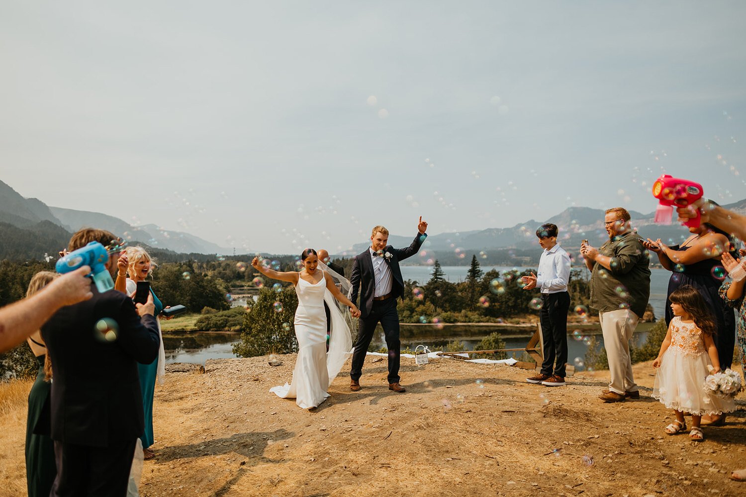 Couple celebrating with guests blowing bubbles after an outdoor elopement ceremony
