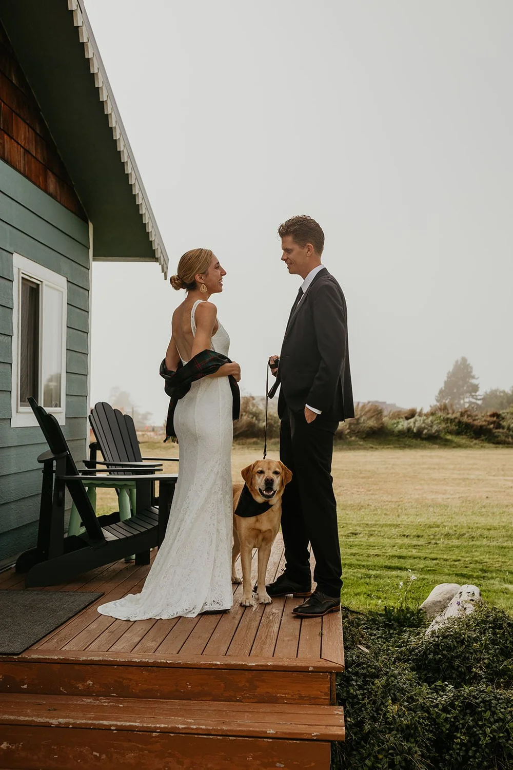 Couple standing on a cabin deck with their yellow lab during a Washington elopement, open landscape stretching behind them