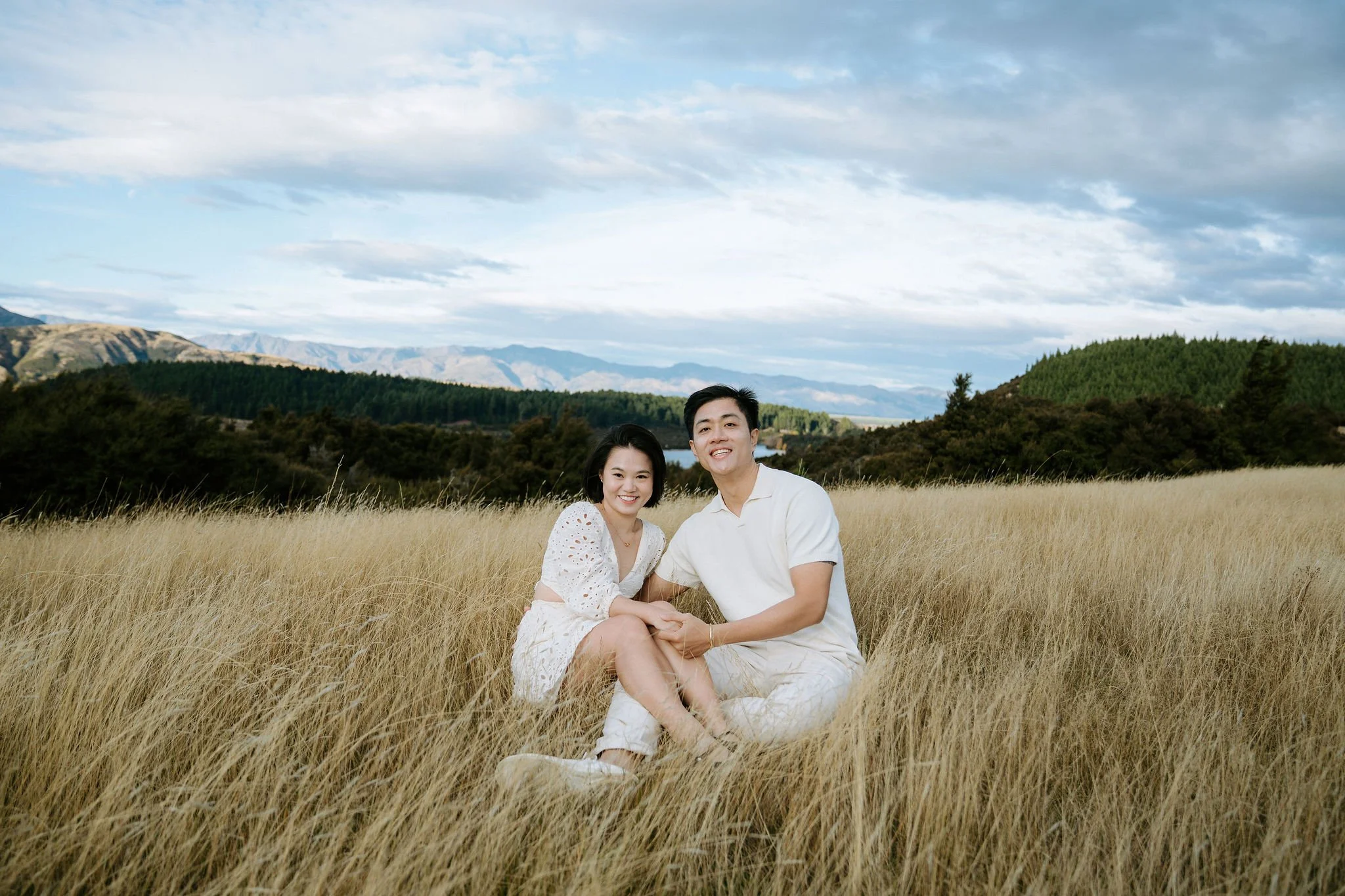 couple sitting together with mountains in the back during shoot in wanaka