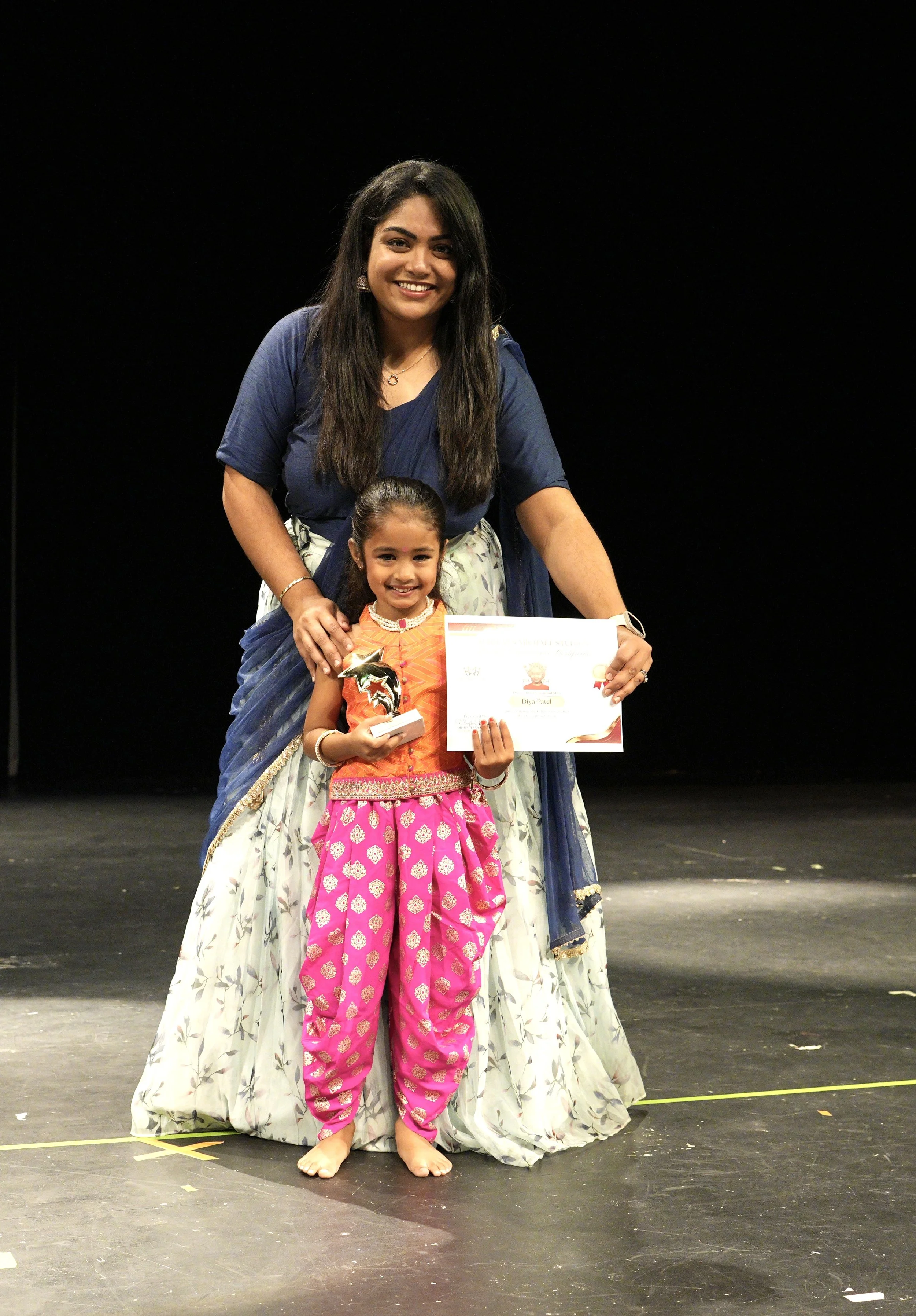 Children in vibrant costumes dancing on stage at fall showcase