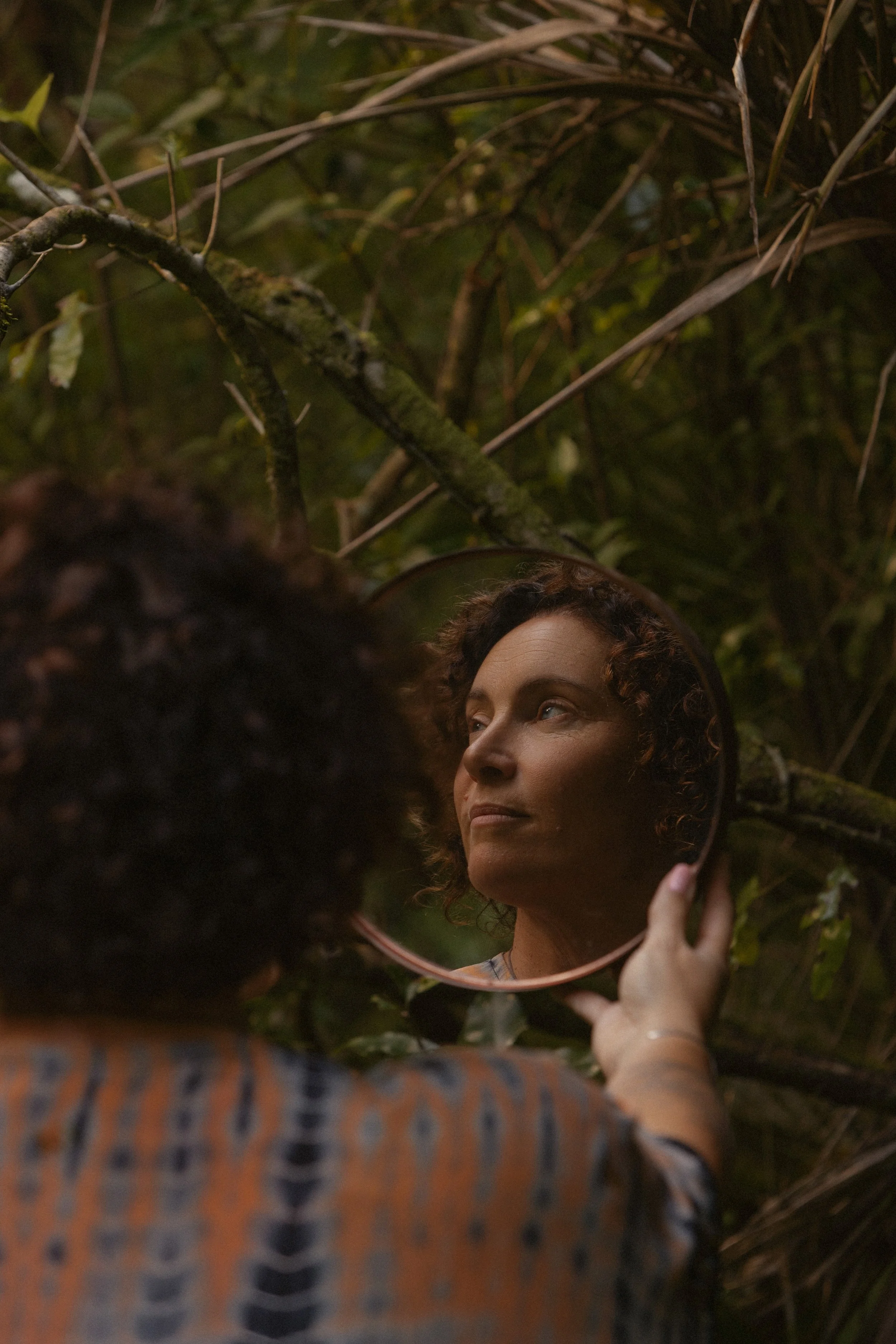 reflection of Michelle Wannan looking into a mirror in nature