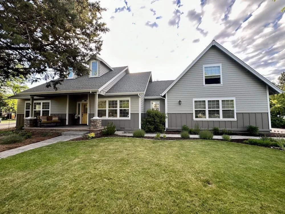 Fresh exterior house painting in Bend Oregon featuring light gray siding with white trim and a welcoming front porch painted by Straight Edge Paint & Finish LLC
