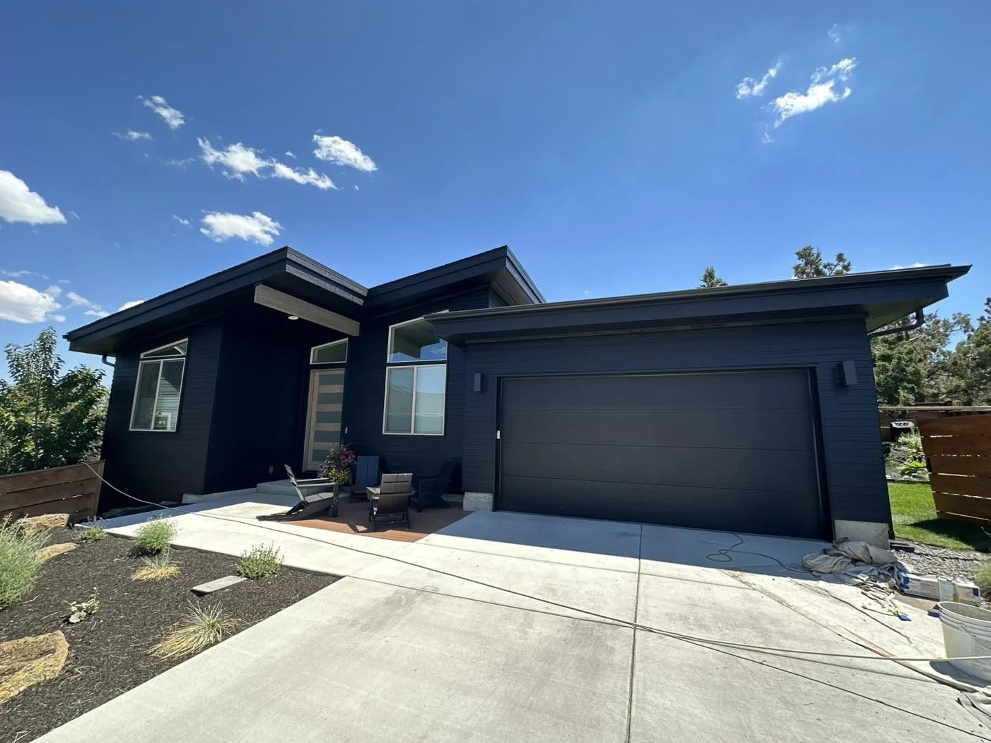 Exterior painting in Prineville Oregon with deep green gray siding black gables white trim and a natural wood front door by Straight Edge Paint & Finish LLC
