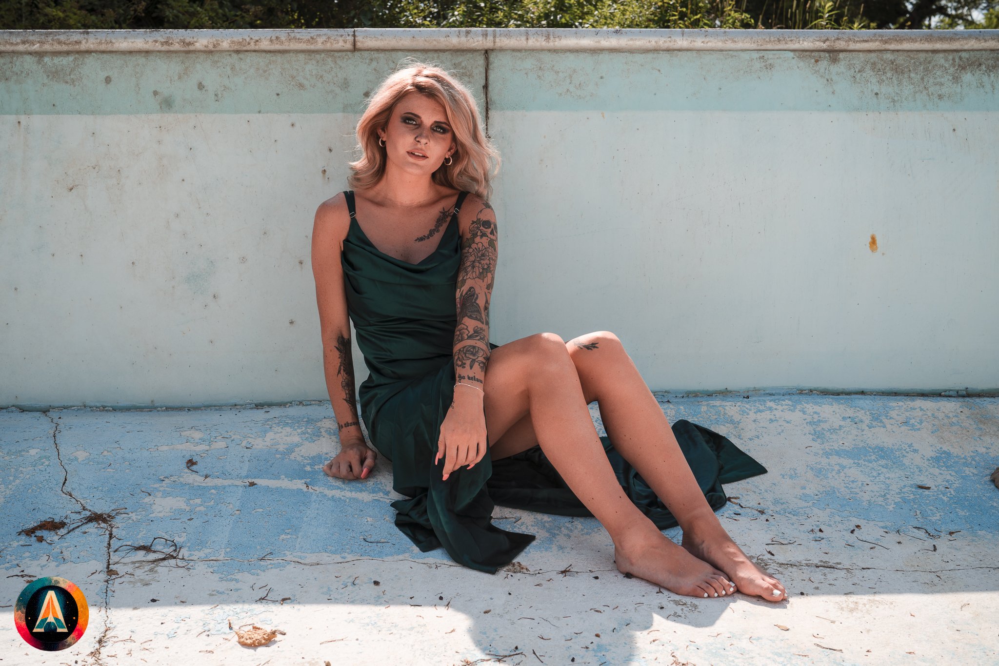 Blonde model courtney france poses in the haunted indiana state sanitarium pool in a elegant black / green dress covered in fake blood.