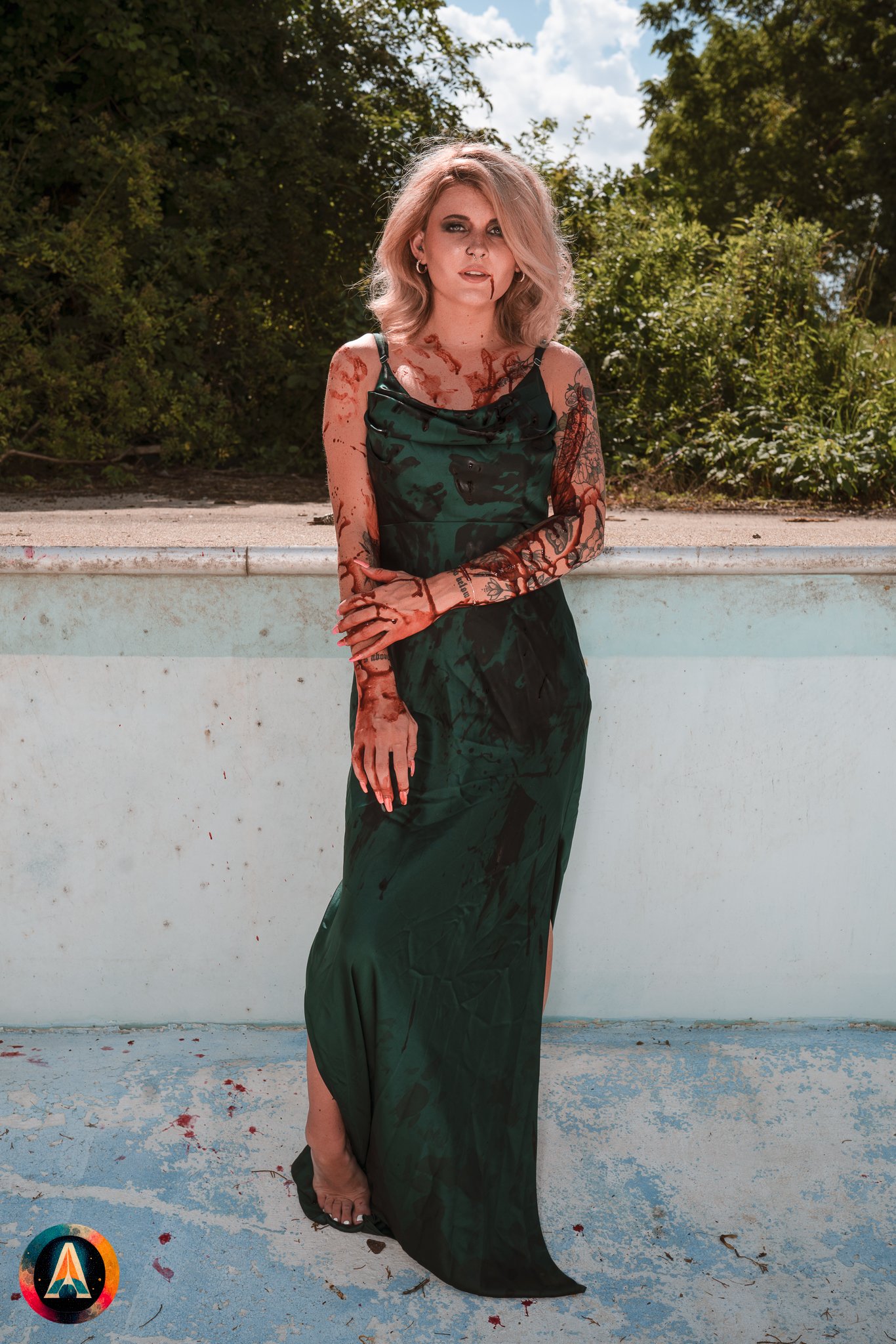 Blonde model courtney france poses in the haunted indiana state sanitarium pool in a elegant black / green dress covered in fake blood.