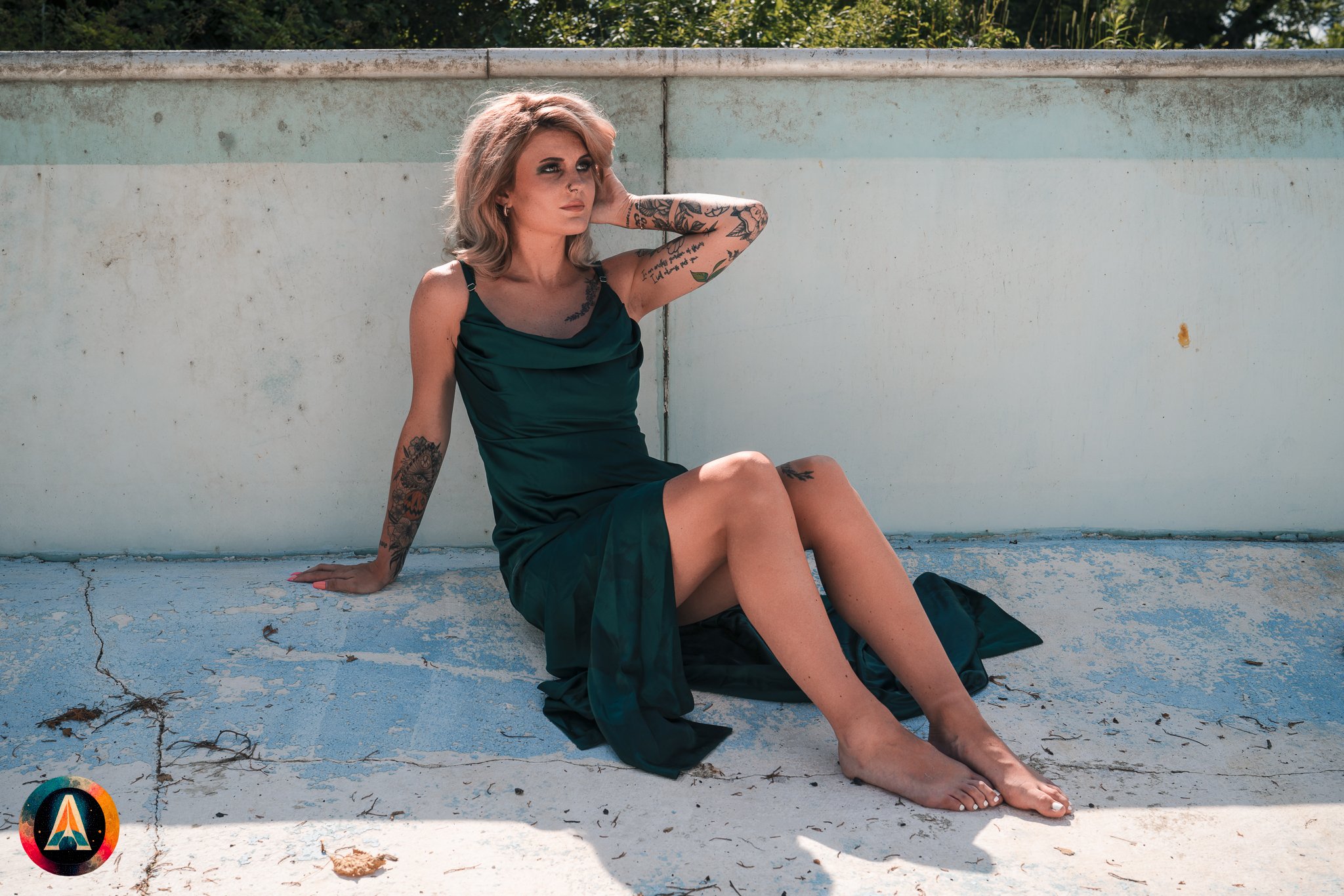 Blonde model courtney france poses in the haunted indiana state sanitarium pool in a elegant black / green dress covered in fake blood.