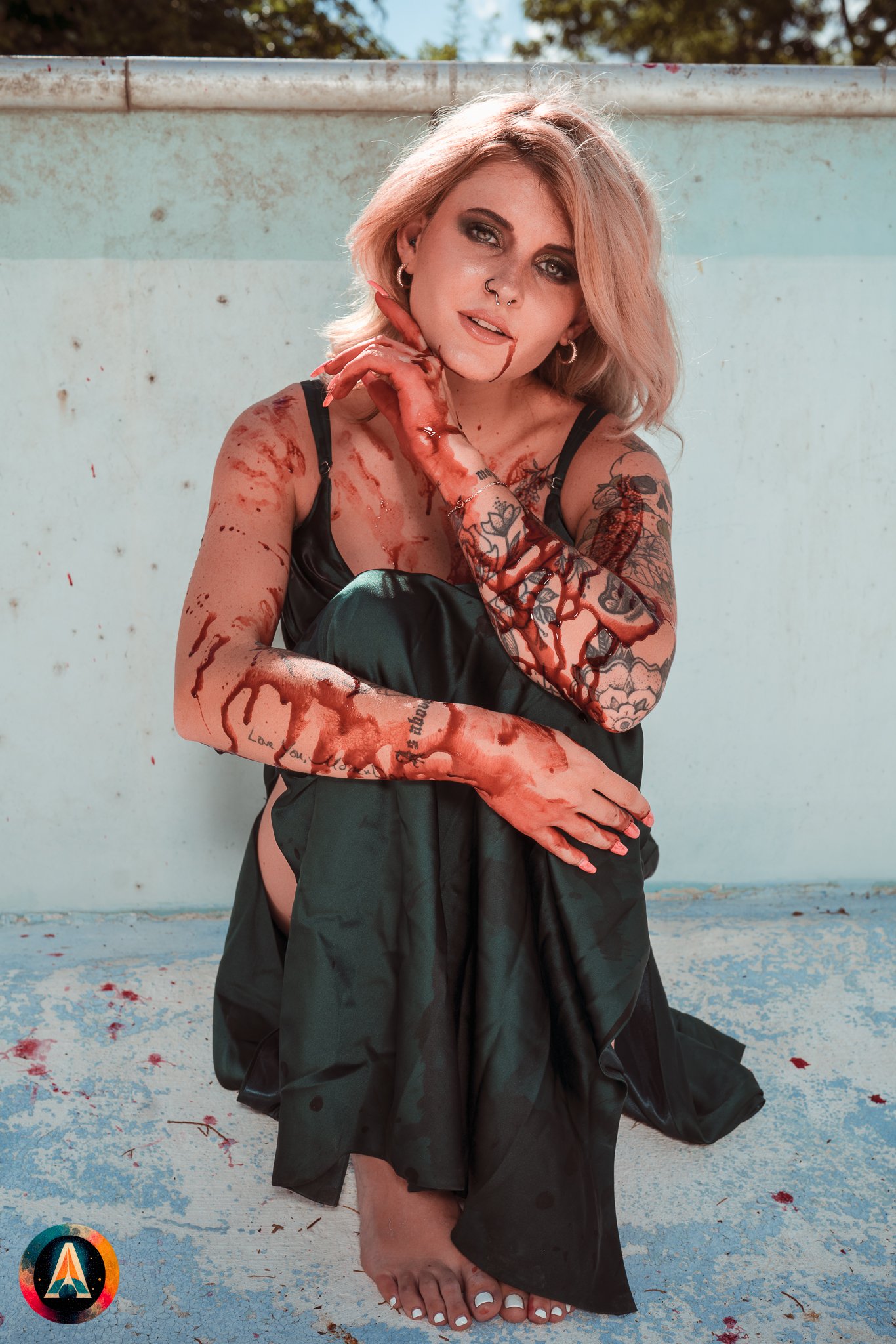 Blonde model courtney france poses in the haunted indiana state sanitarium pool in a elegant black / green dress covered in fake blood.