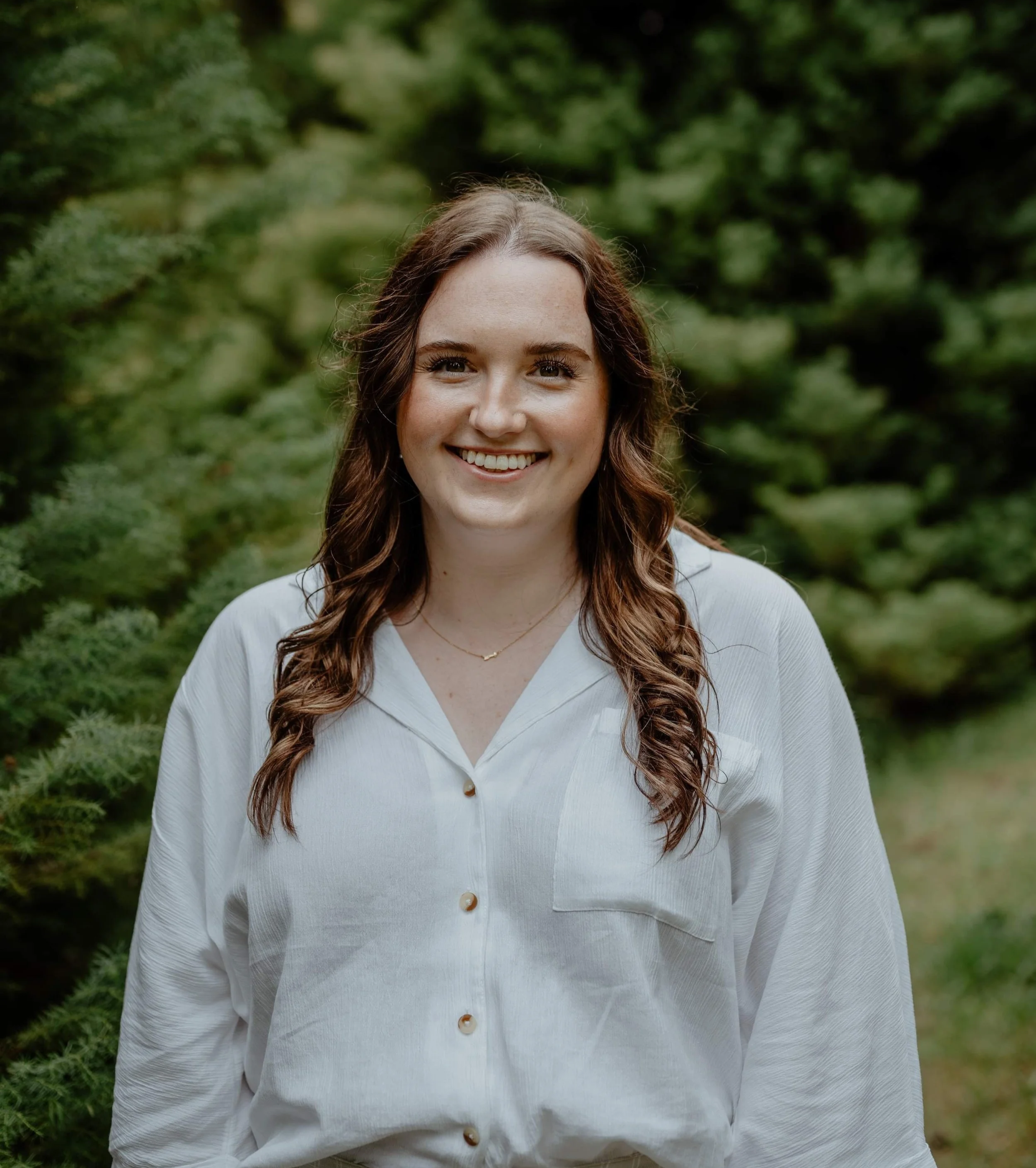 Trauma Counsellor smiling warmly with trees in background.