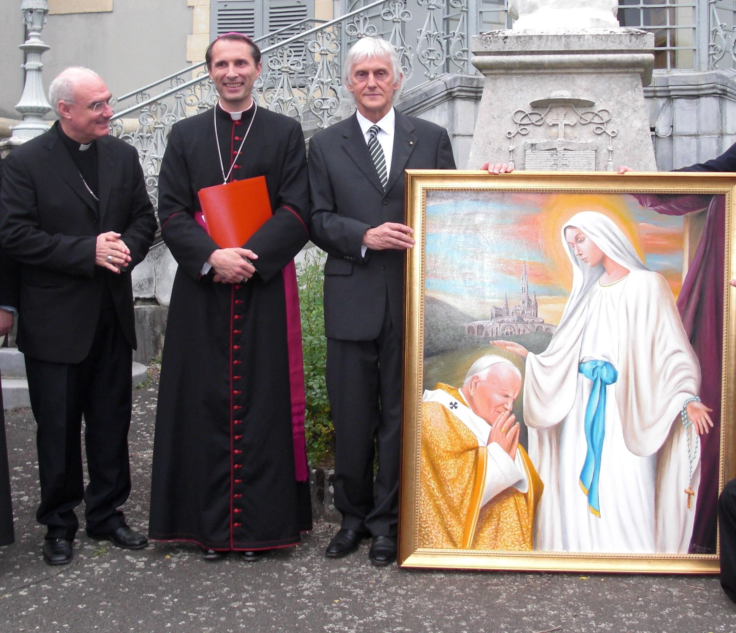 38-	Durante il 54° Pellegrinaggio Militare Internazionale a Lourdes: consegna dell’opera pittorica “Giovanni Paolo II prega al cospetto della Madonna di Lourdes” a S. Ecc. Mons. Nicolas Brouwet, Vescovo di Lourdes. L’opera è conservata nella sede del