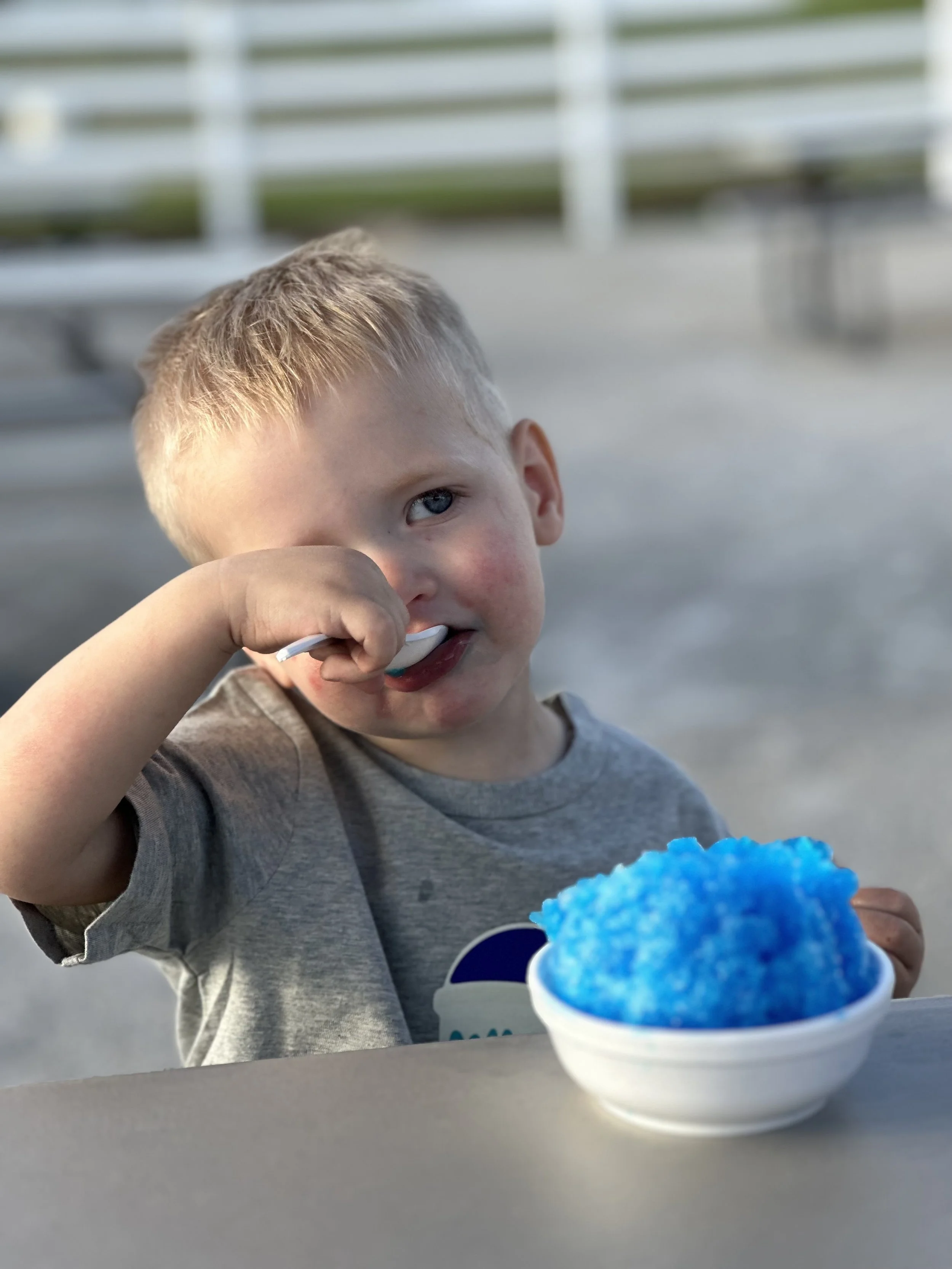 Young boy eating a blue snow cone.