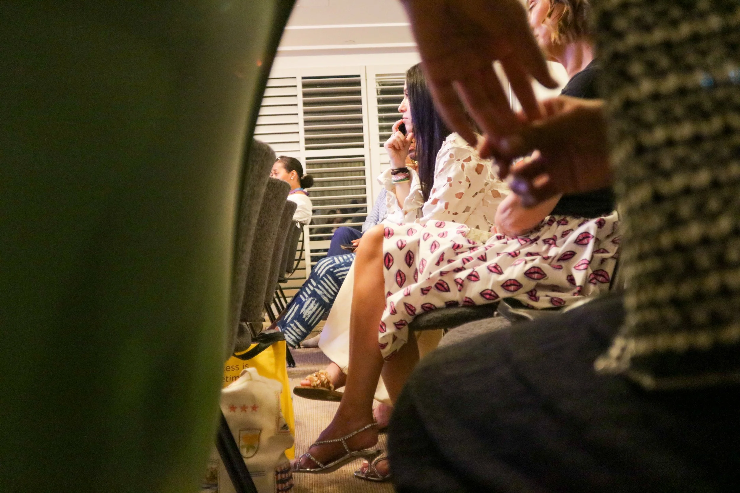 Acoustics of Proximity: A deep-focus shot emphasizing the spatial dynamics of the audience. The foreground element creates an acoustic "frame," drawing the viewer's eye to the subjects in the mid-ground, whose specific attire, a vibrant intersection 