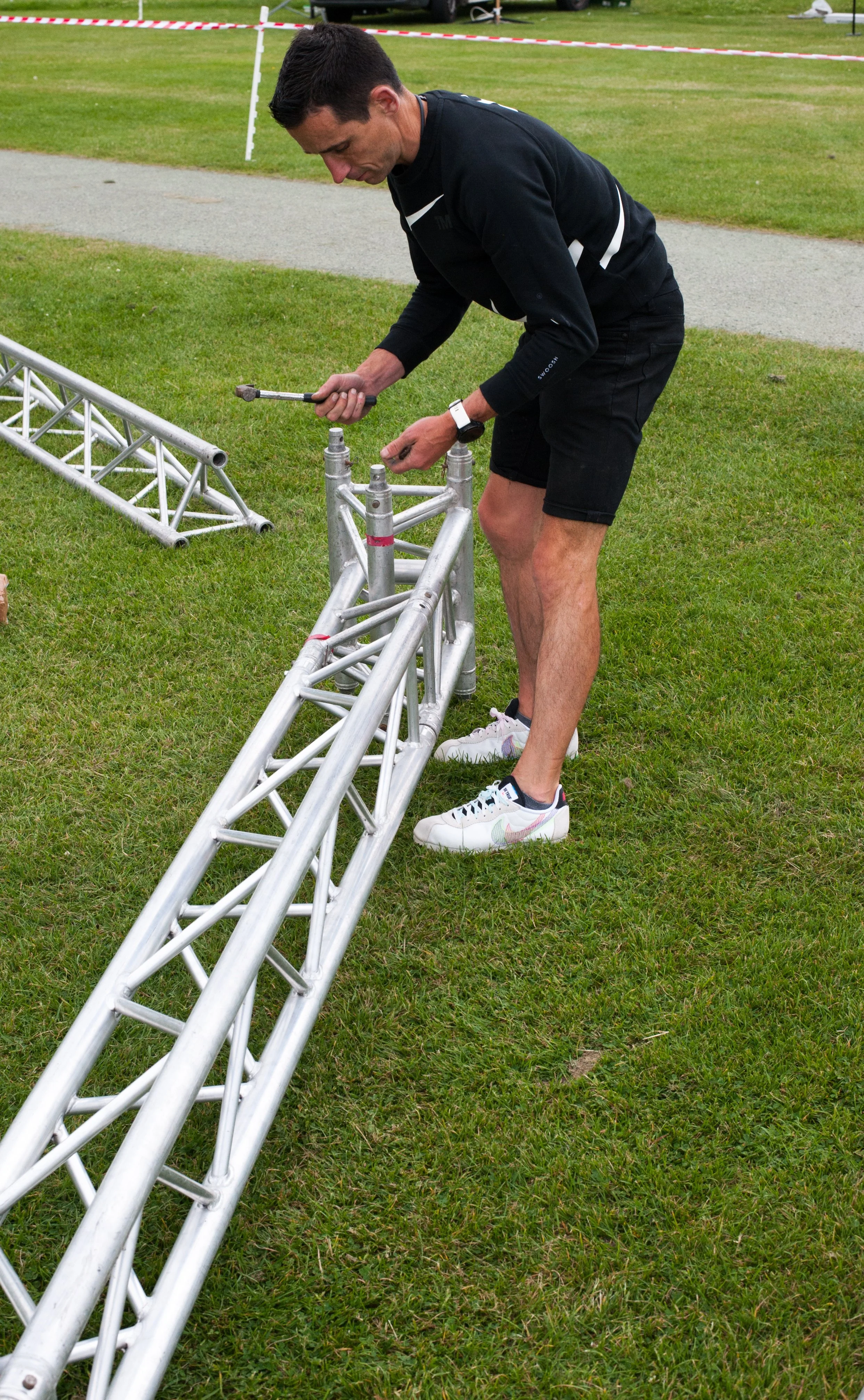 Person assembling metal truss on grass