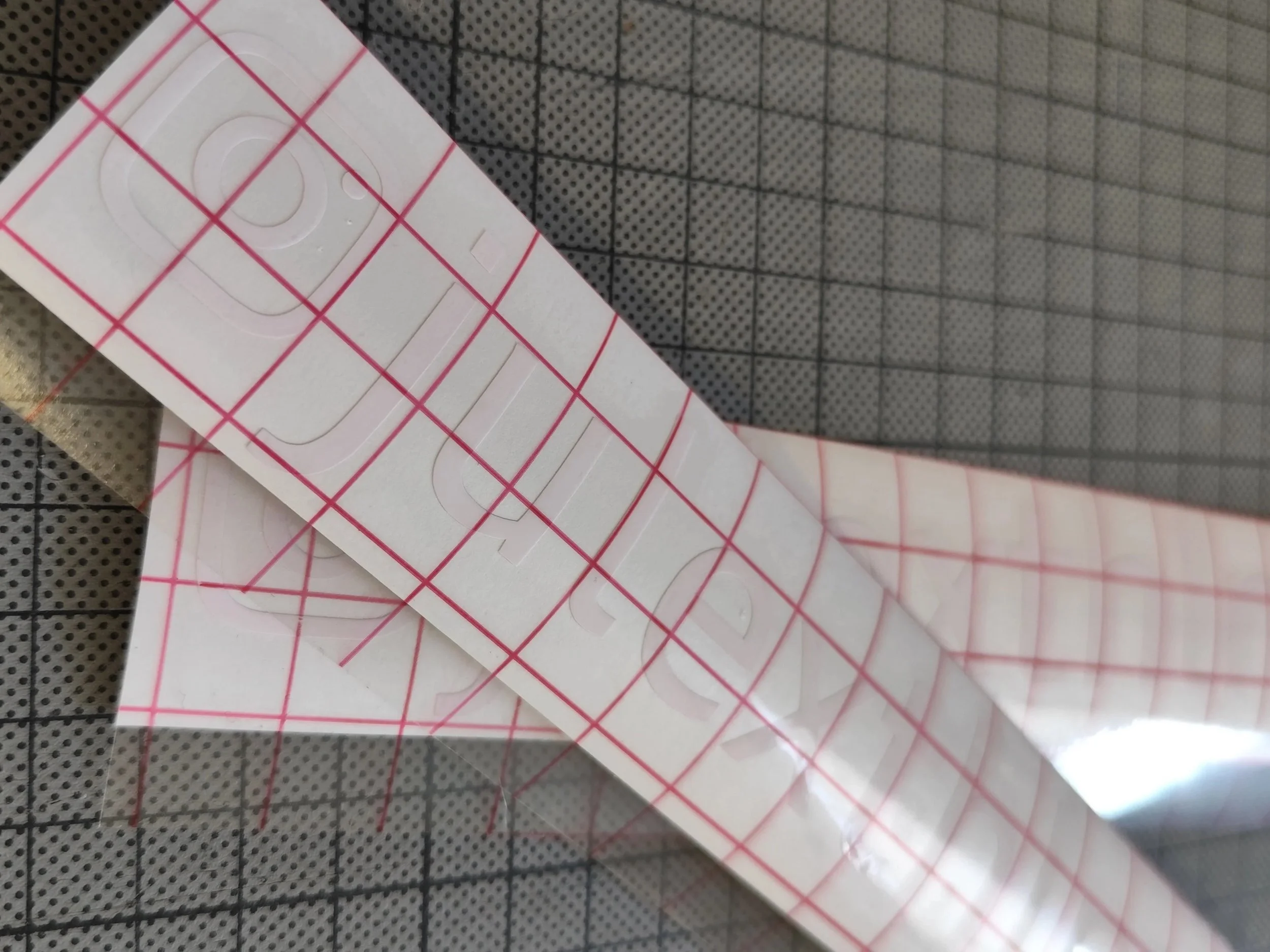 Auf einem Schneidebrett liegt eine Rolle mit weißen Aufklebern, die mit roten Linien in Quadrate und andere Formen unterteilt sind.