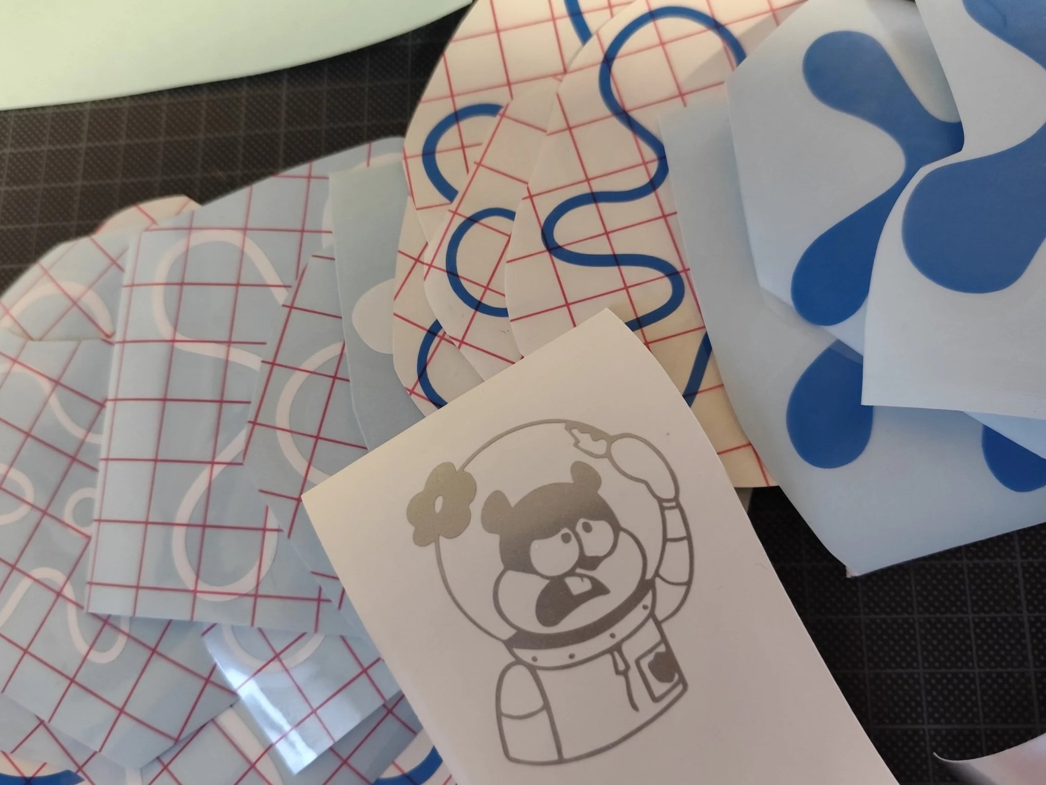 Verschiedene Aufkleber von Spongebob Blumen in blau und weiß sowie eine graue Zeichenzeichnung von Sandy in einem Astronautenanzug.