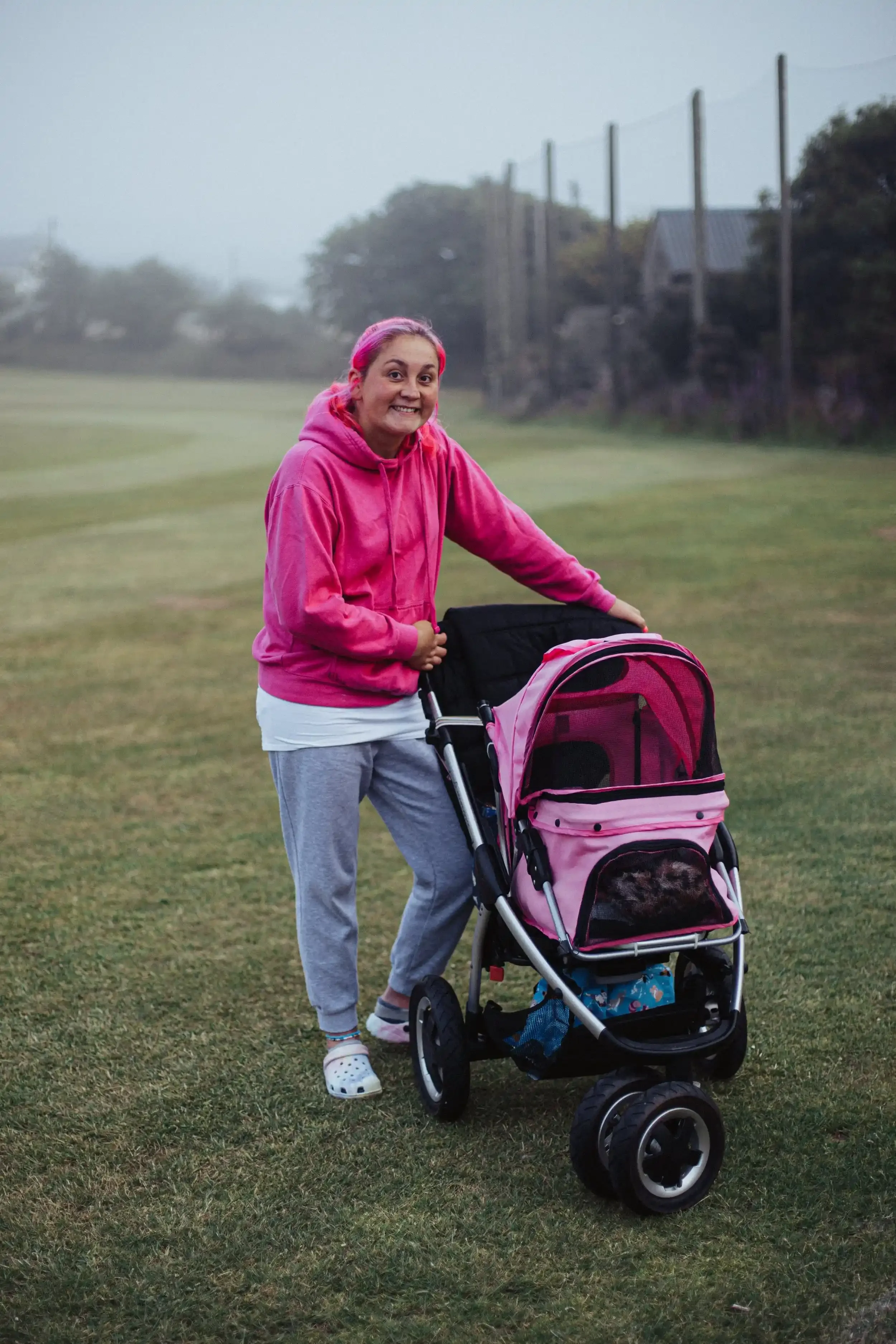 A portrait of a supporter with pink hair and a dog in a pram at Wendron Cricket Club, from the award-winning Seaview Old Boys series by Matthew Morgan.