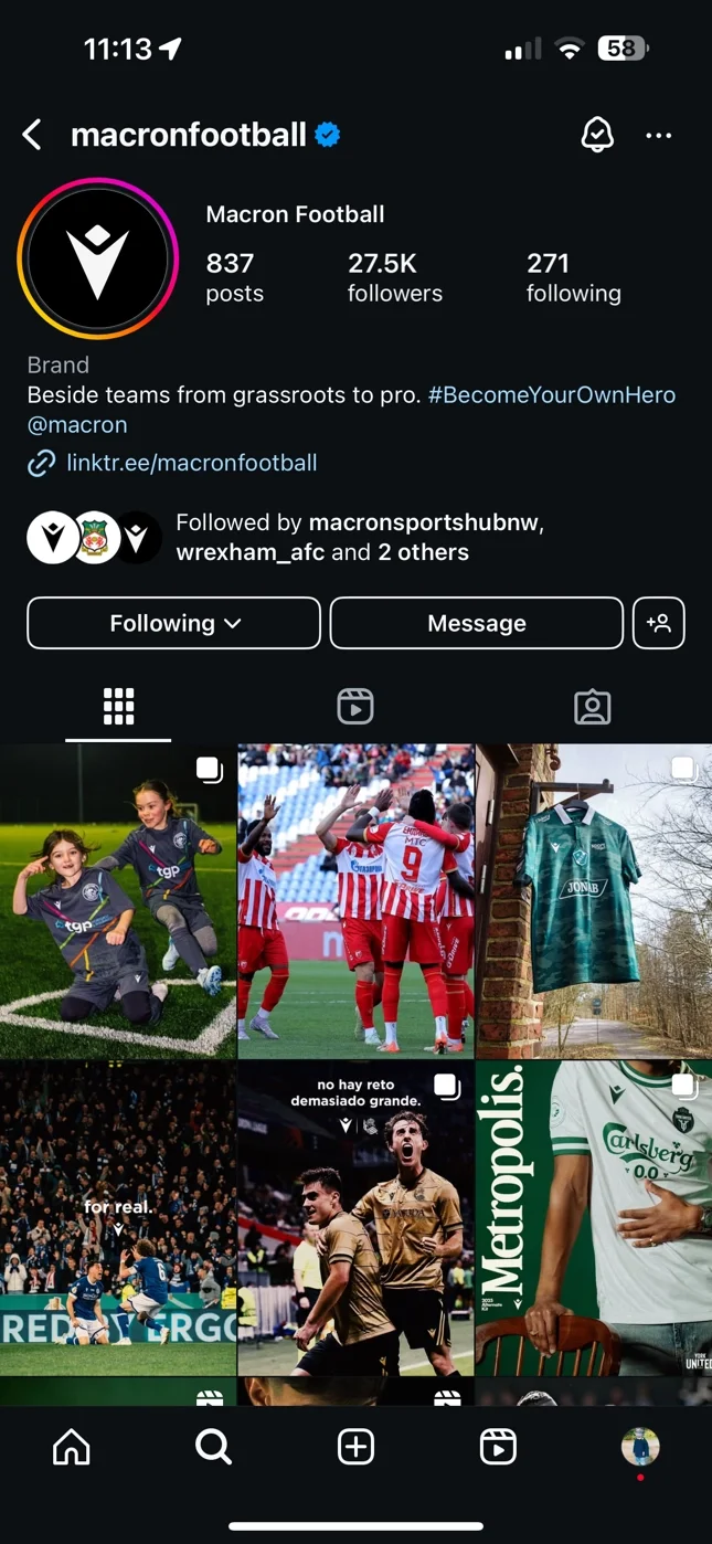 A screenshot of the Macron Football official Instagram profile. The top-left post in the image grid features a photograph by Matthew Morgan showing two young Pen-Y-Cae FC players celebrating on a pitch. The profile has over 27,000 followers and inclu