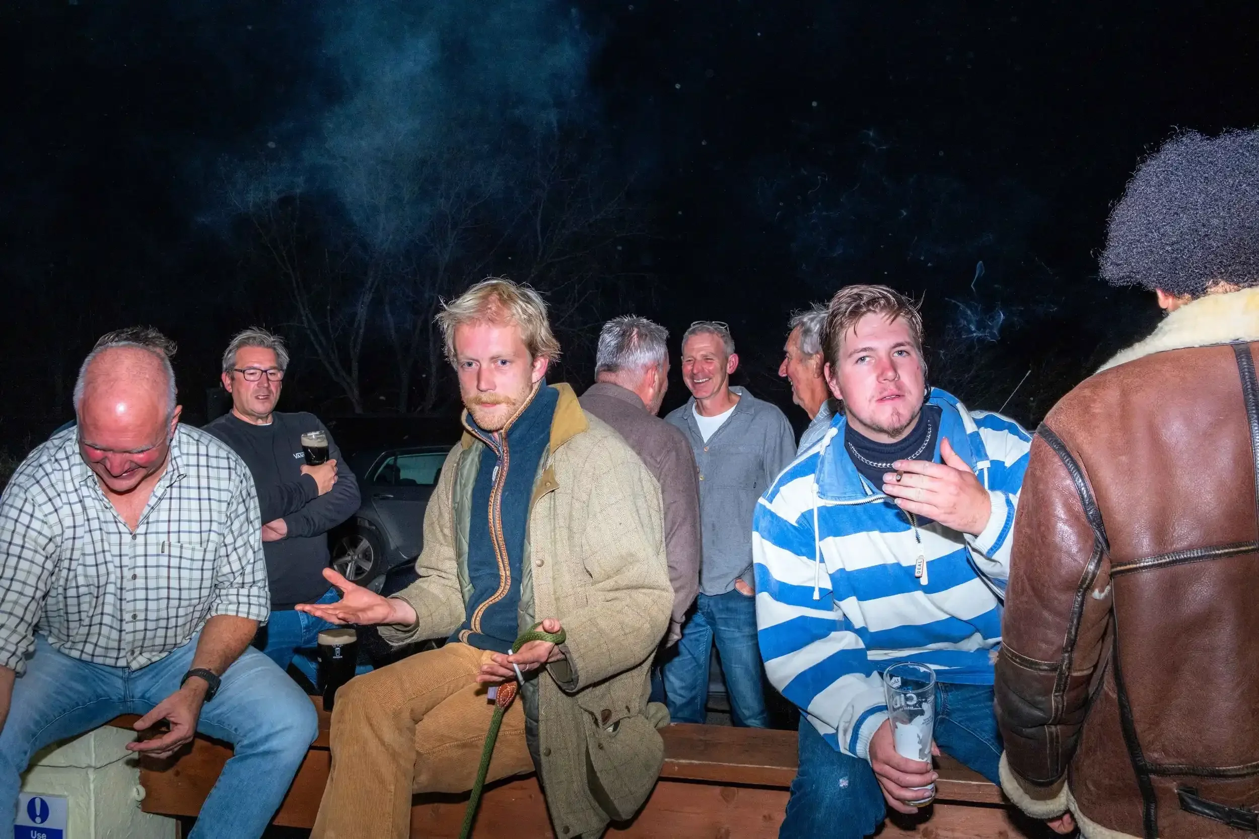 A group of local regulars talking and laughing in the smoking area of the Seaview Inn at night, from Matthew Morgan's documentary book 'Proper Pub'