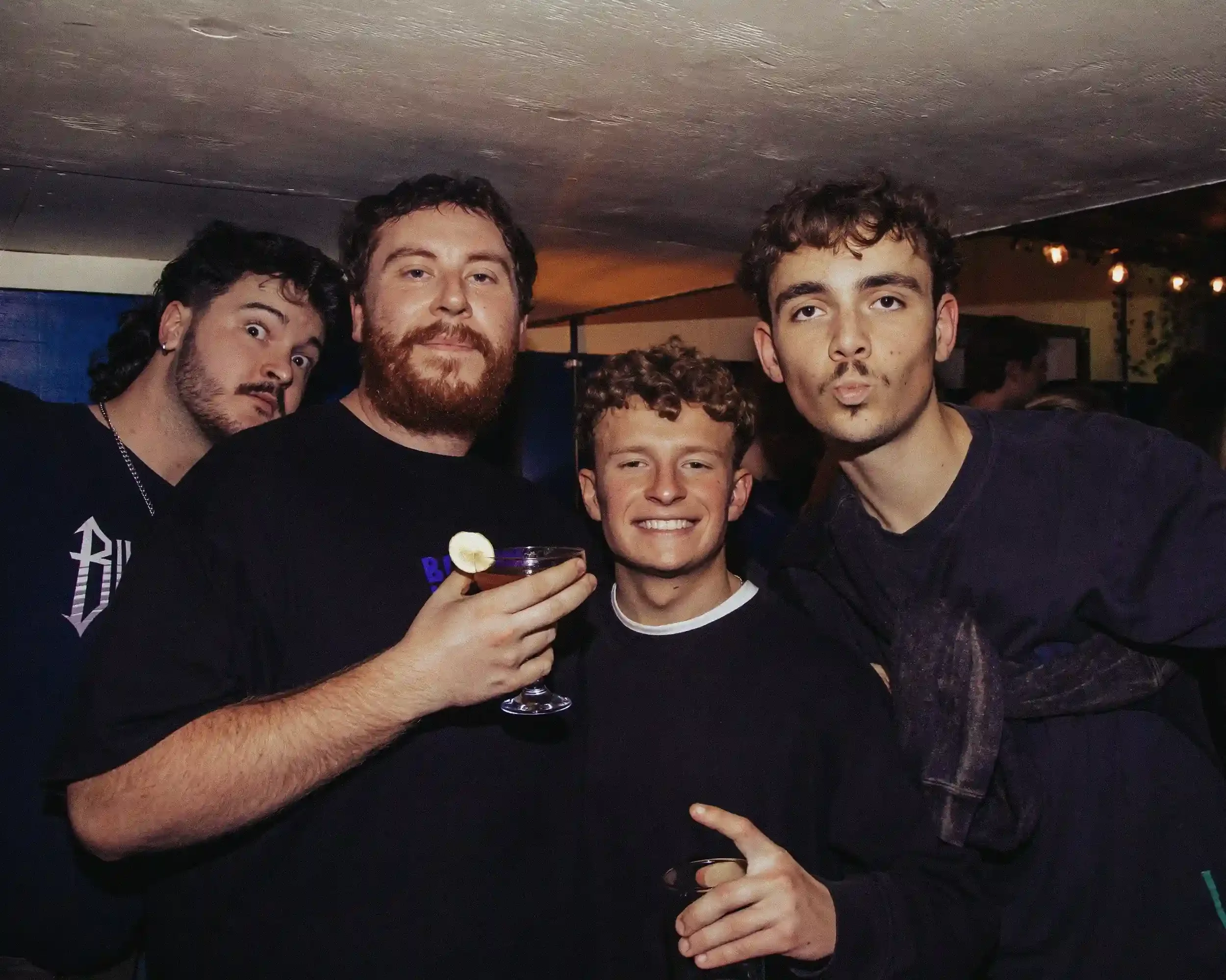 Authentic documentary nightlife photography by Matthew Morgan at Small Ships bar. This group portrait, captured during a charity fundraiser, highlights the gritty yet welcoming '5-star dive bar' atmosphere and the vibrant social subculture of the ven