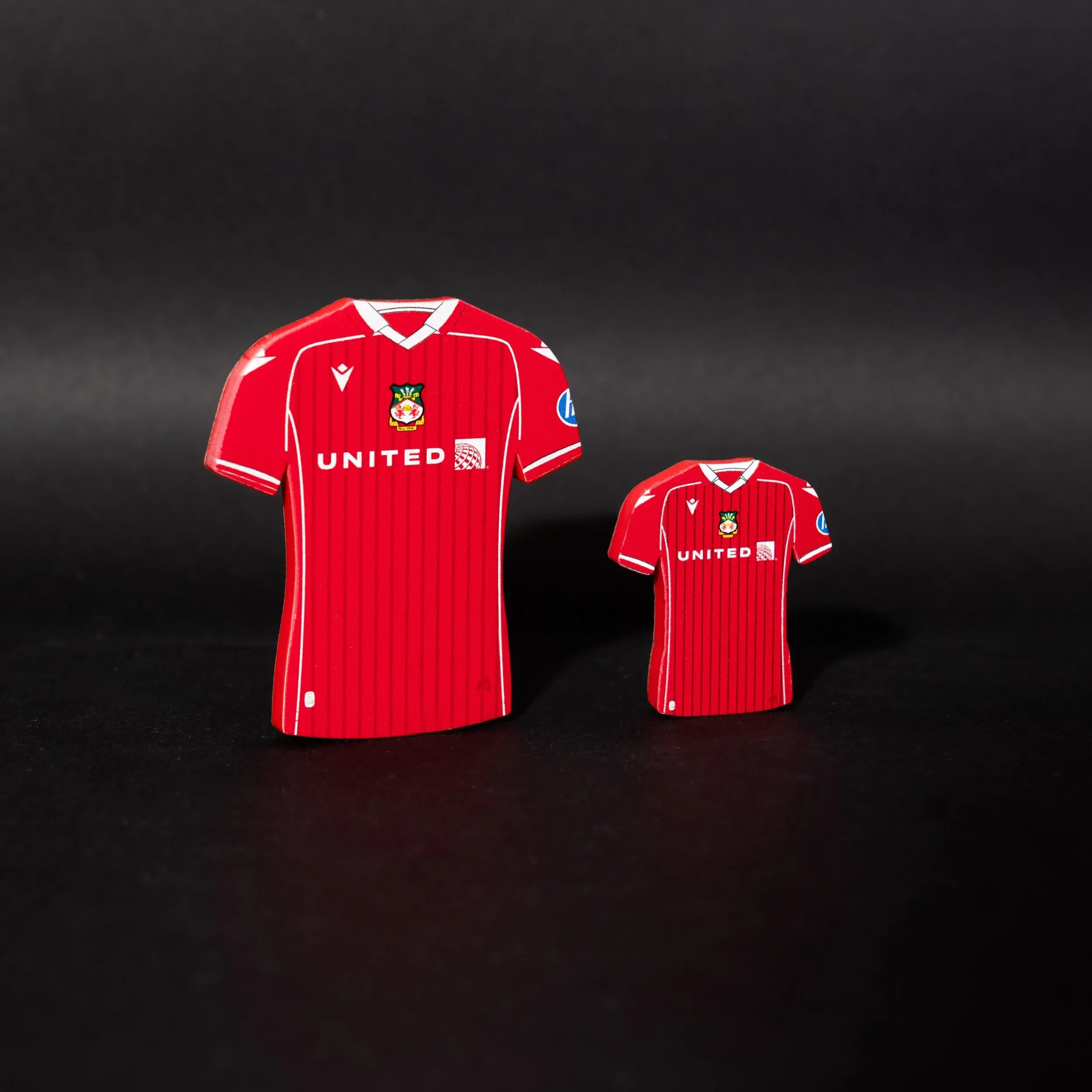 A high-resolution product shot of two Wrexham AFC home kit tactical magnets by Your Game Your Name. The magnets are shaped like the official red home jersey with white pinstripes, the Wrexham crest on the chest, and the United Airlines sponsor logo. 
