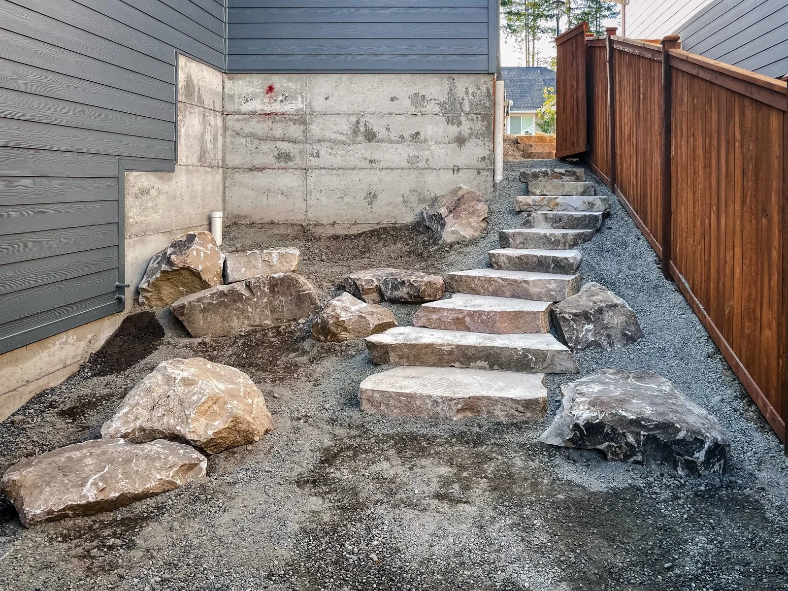 Stone stairs in a side yard next to cedar fence.
