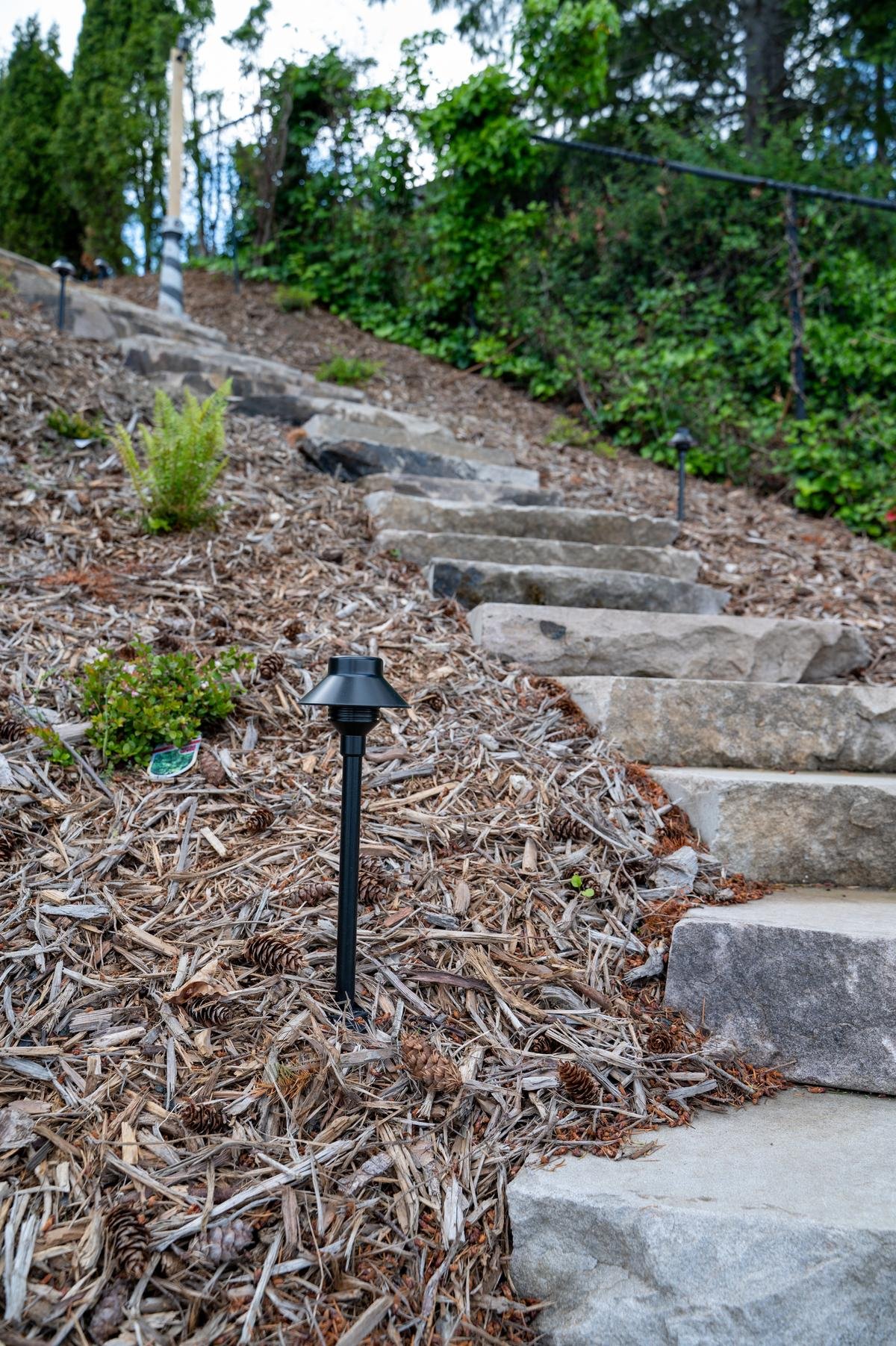 Black pathway light at the base of a stone staircase.
