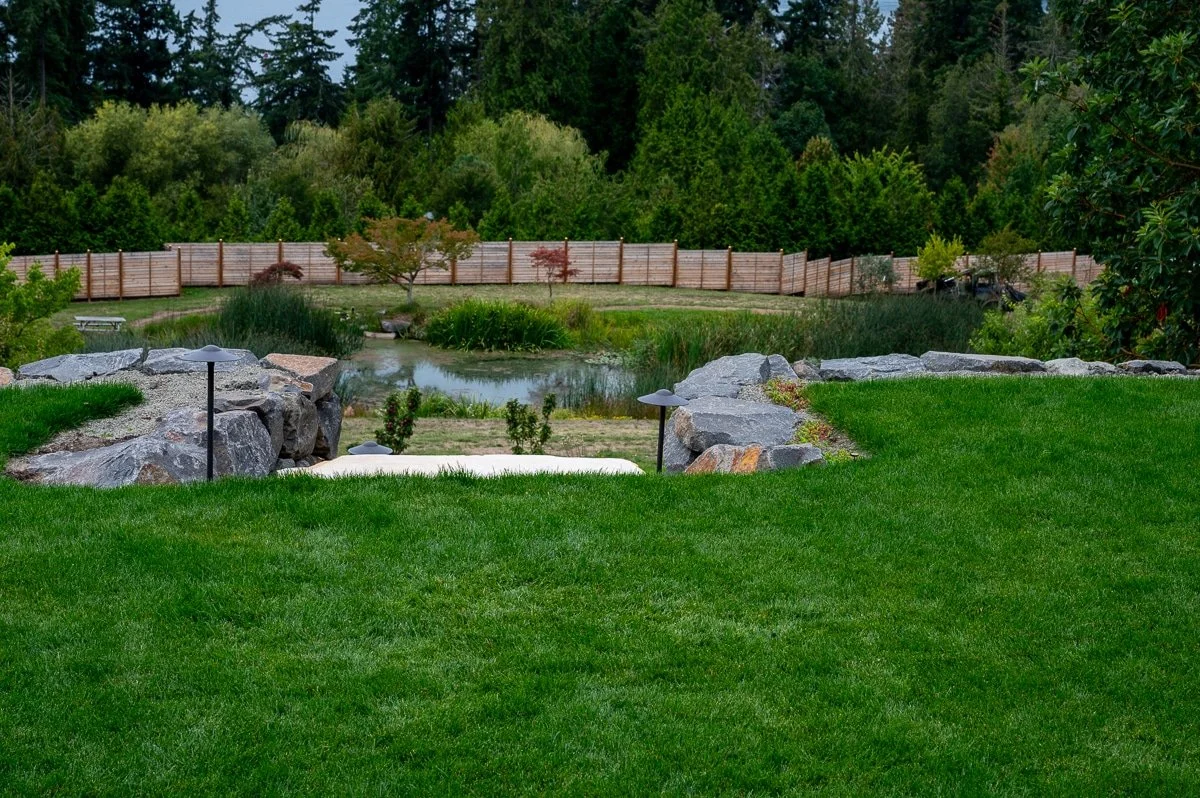 Vibrant green lawn with stone stairs leading to a pond.