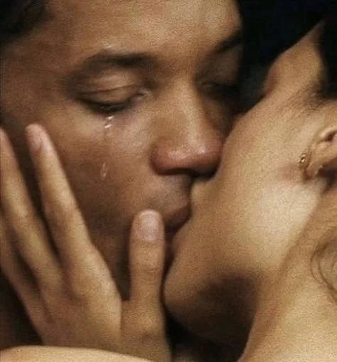 Close-up of two people kissing emotionally, one with a tear.
