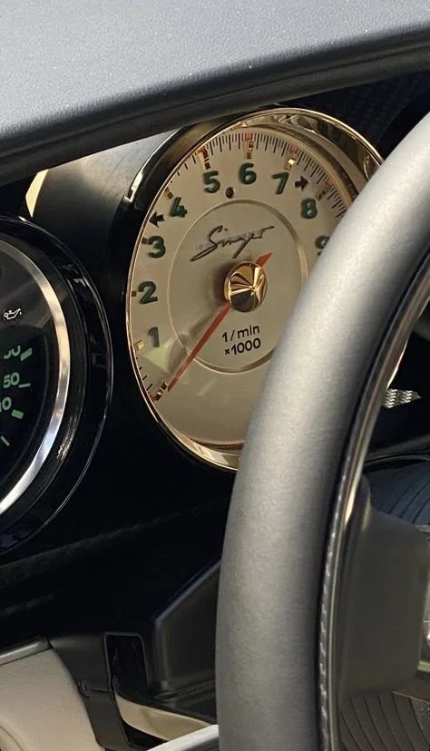 Luxurious car tachometer displaying RPM with brand signature.