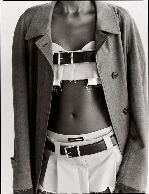 Fashion model wearing a tailored jacket with belted top and skirt, black and white photo.